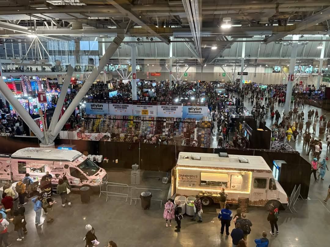 An aerial view of a large convention center filled with people and food trucks.