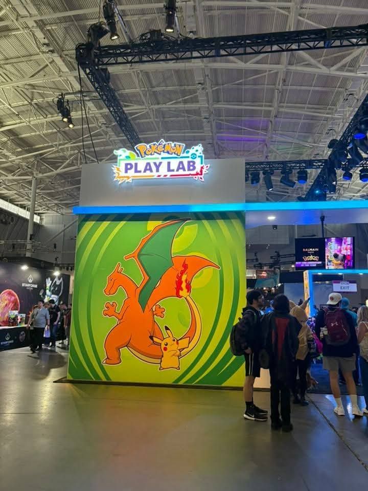 A group of people are standing in front of a pokemon play lab.