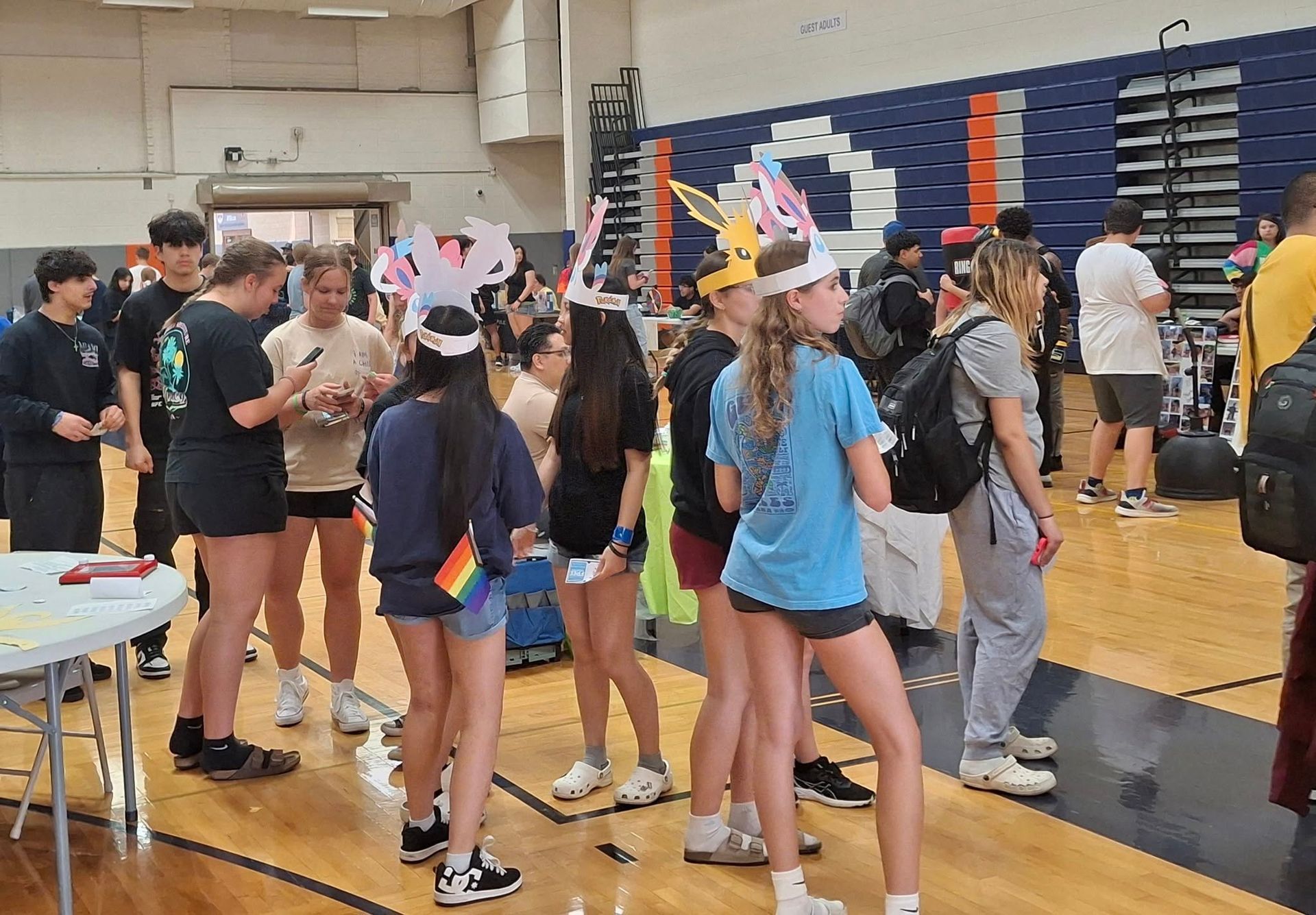 A group of people are standing in a gym wearing unicorn hats.