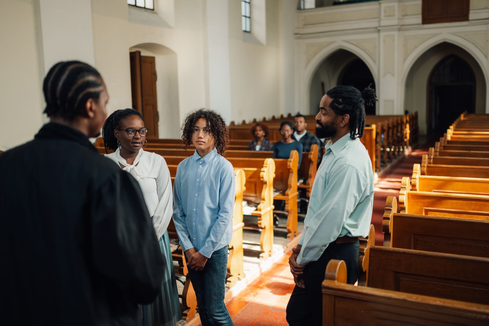 A group of people are standing in a church talking to each other.