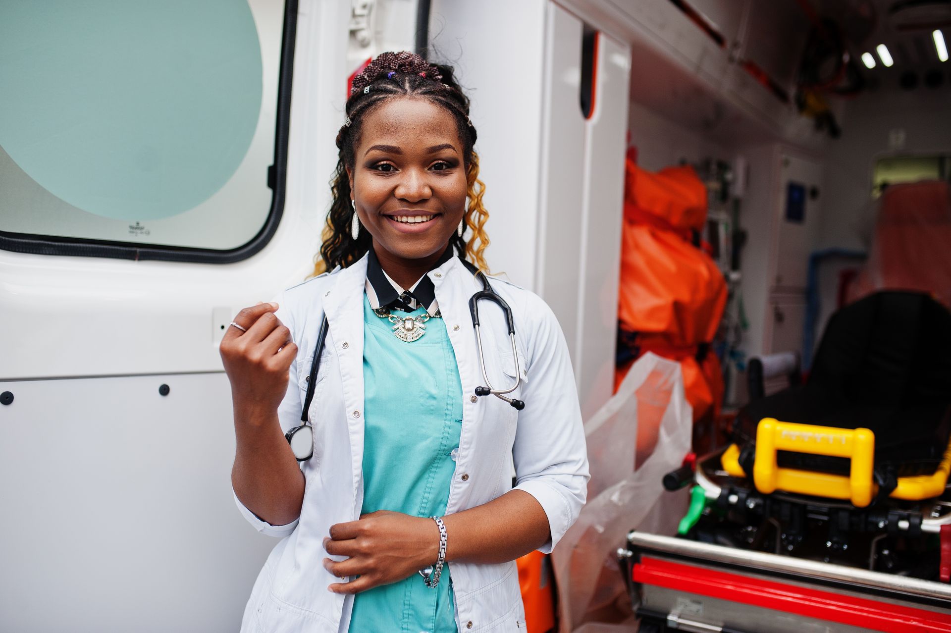 A female doctor is standing in front of an ambulance.