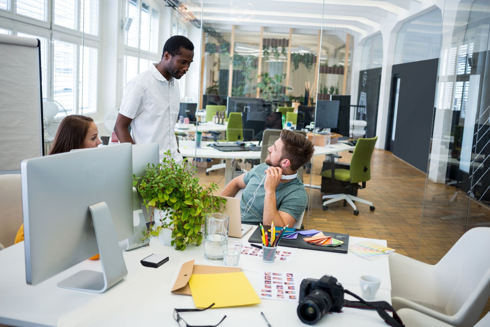 A man is sitting at a desk in an office talking to another man.