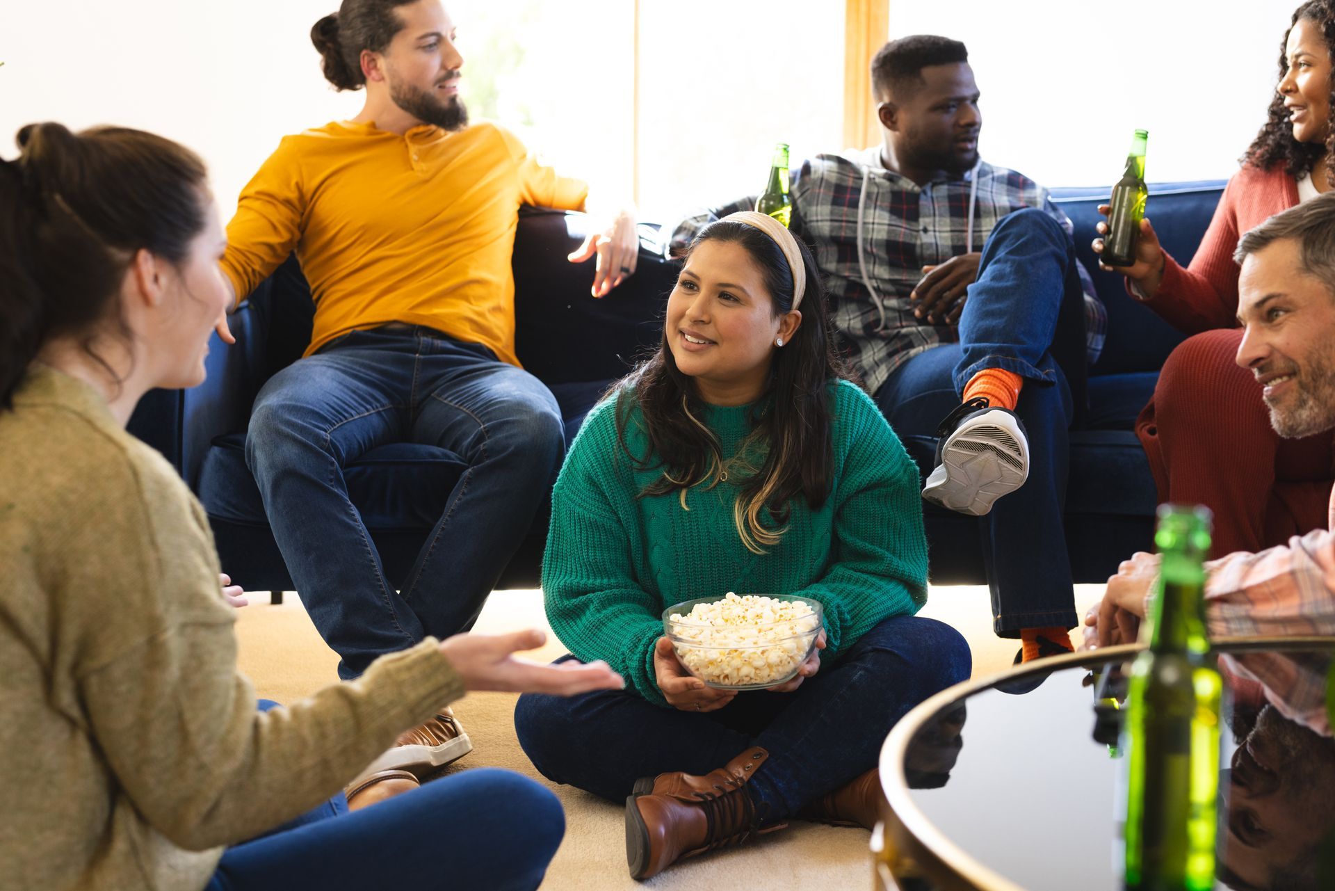 A group of people are sitting on the floor eating popcorn and drinking beer.