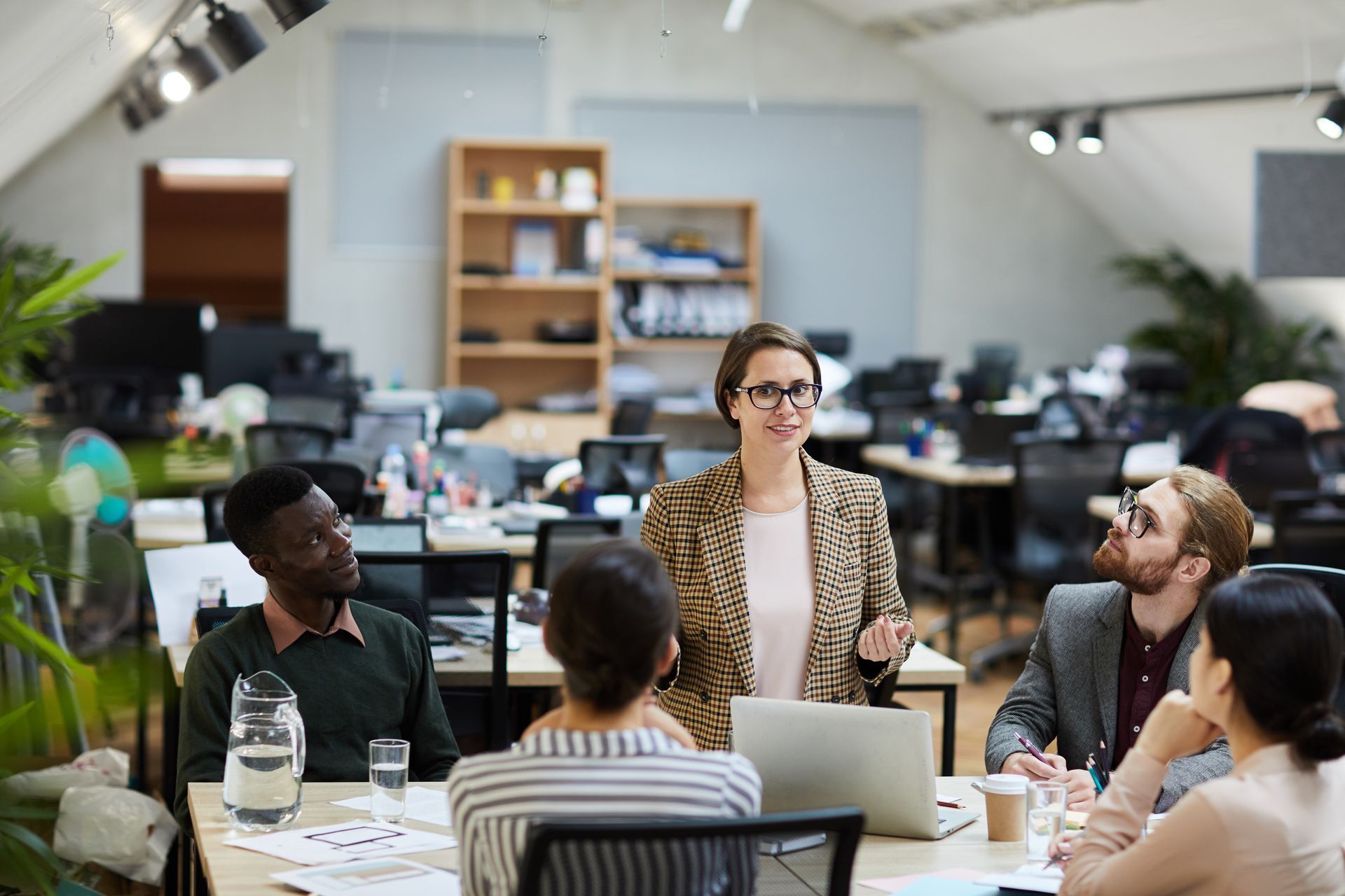 A woman is giving a presentation to a group of people in an office.