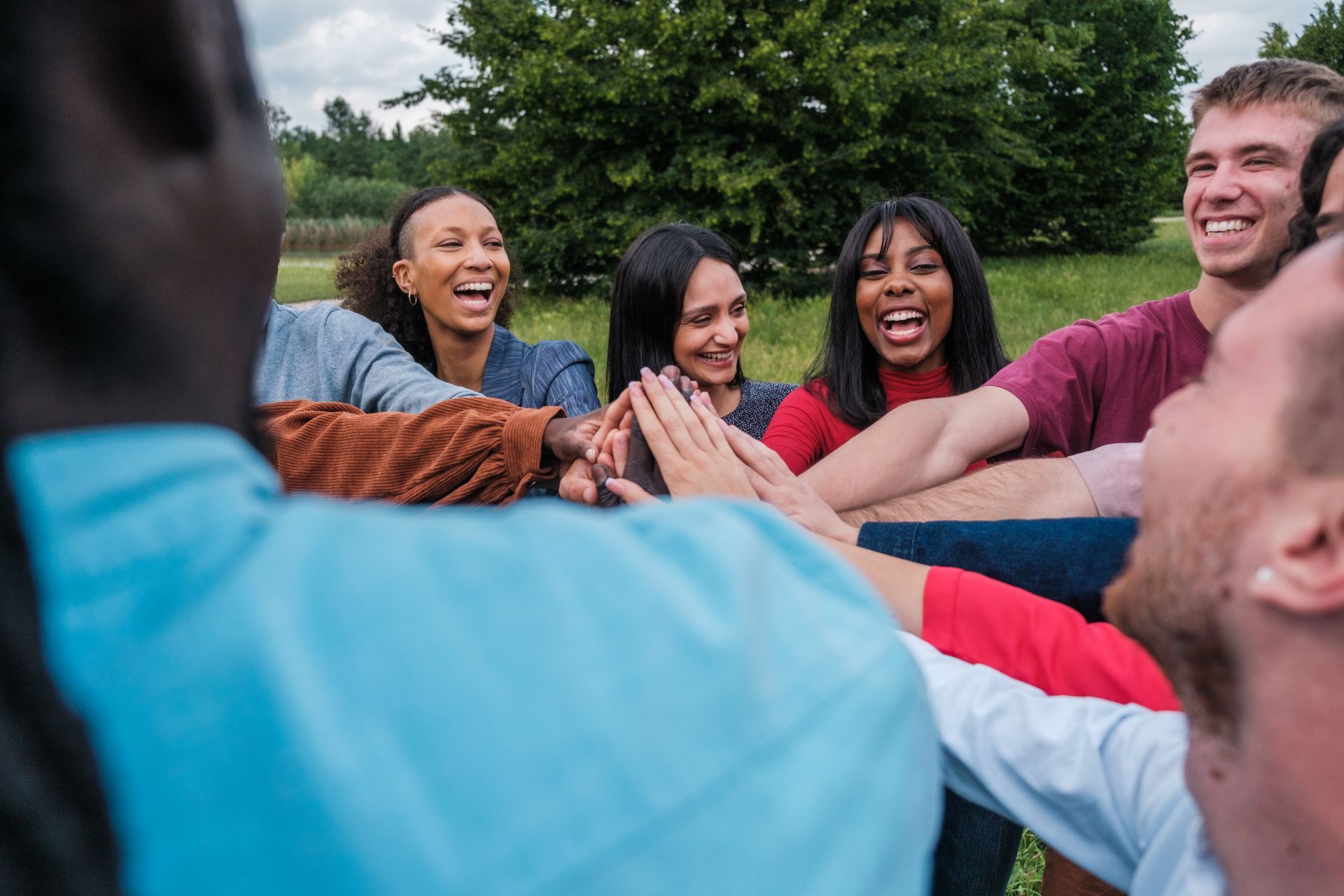 A group of people are putting their hands together in a circle.
