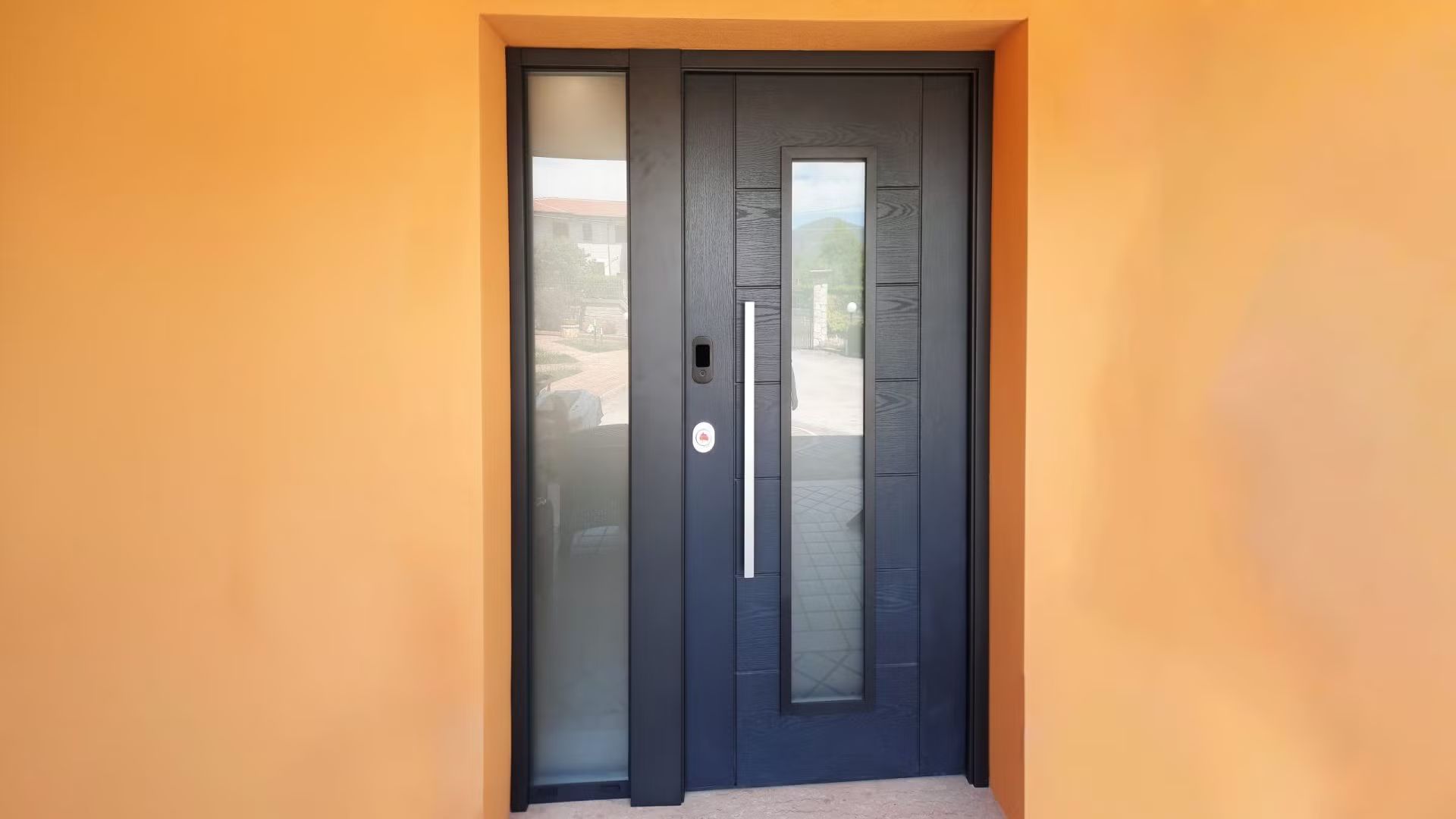 Una porta nera con un pannello di vetro sul lato di un edificio.