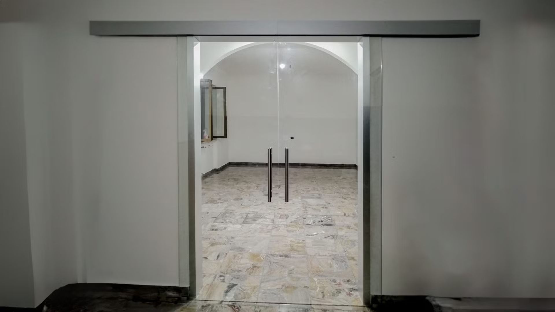 Una porta scorrevole in vetro è aperta su una stanza vuota.