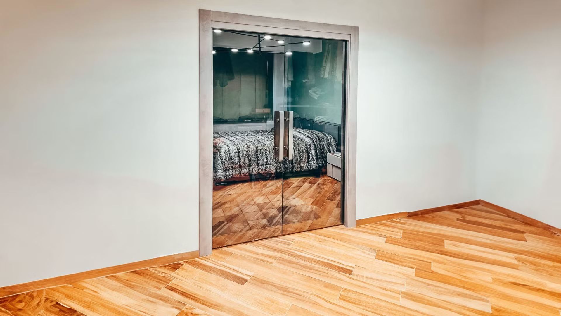 Una stanza vuota con un pavimento in legno e una porta a vetri.