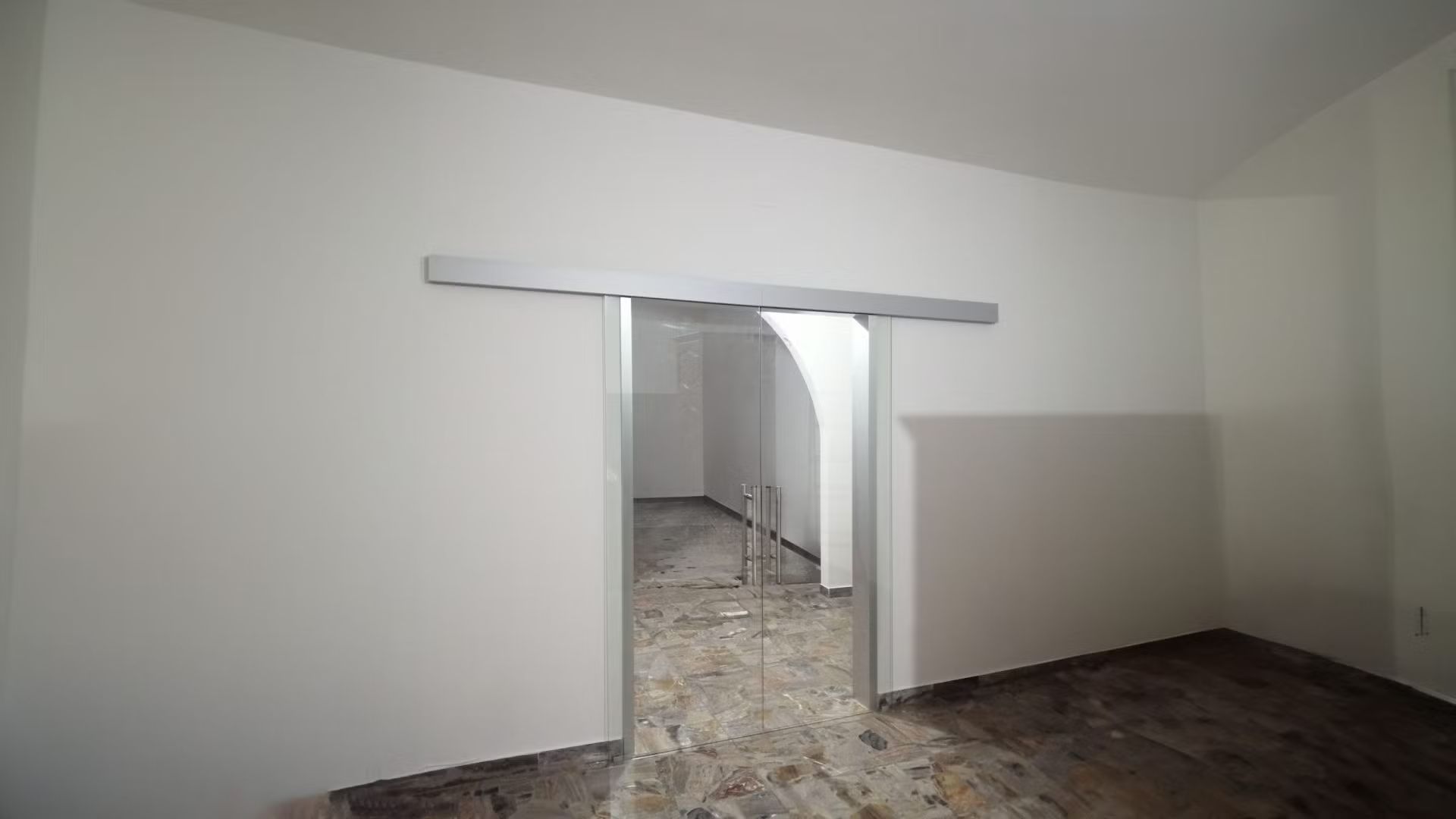 Una stanza vuota con una porta scorrevole in vetro che conduce ad un'altra stanza.
