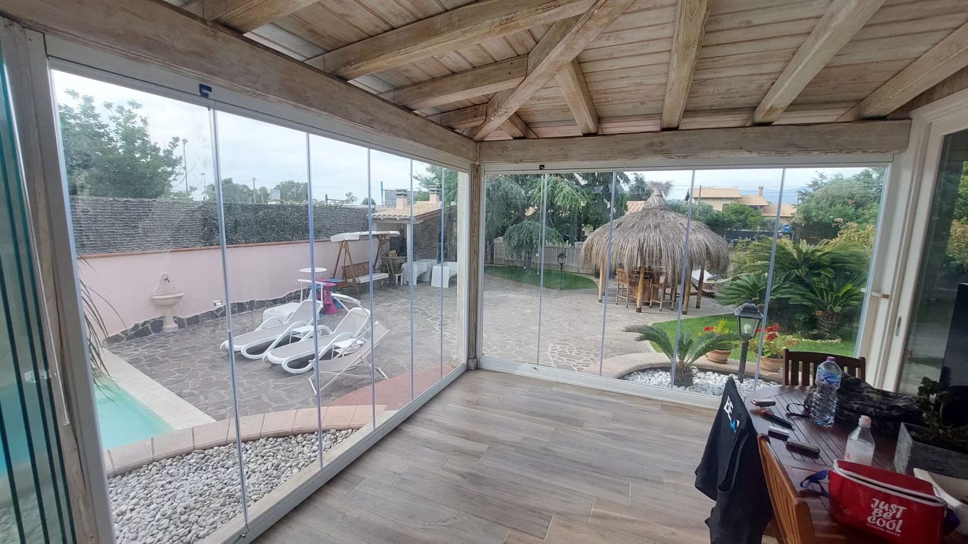 Una stanza con un tavolo e delle sedie e una piscina sullo sfondo.