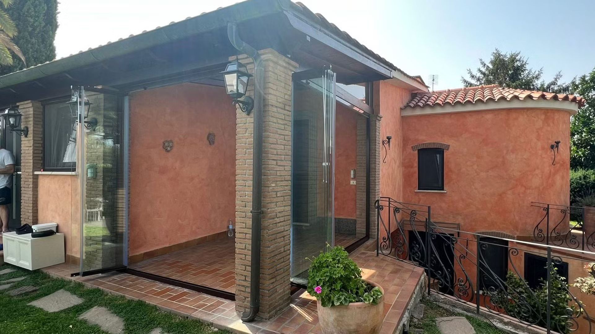 Una casa con un patio e una pianta in vaso davanti.