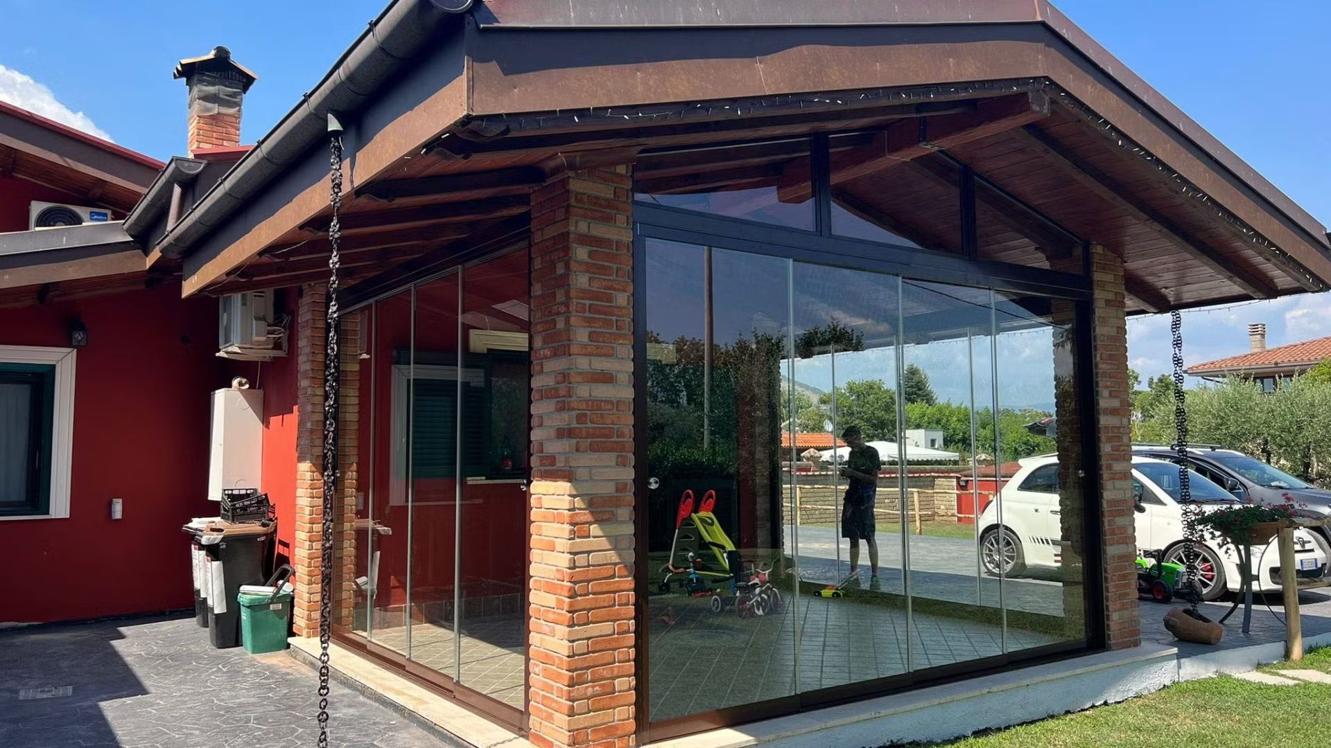 Una casa rossa con un grande portico coperto di vetro.