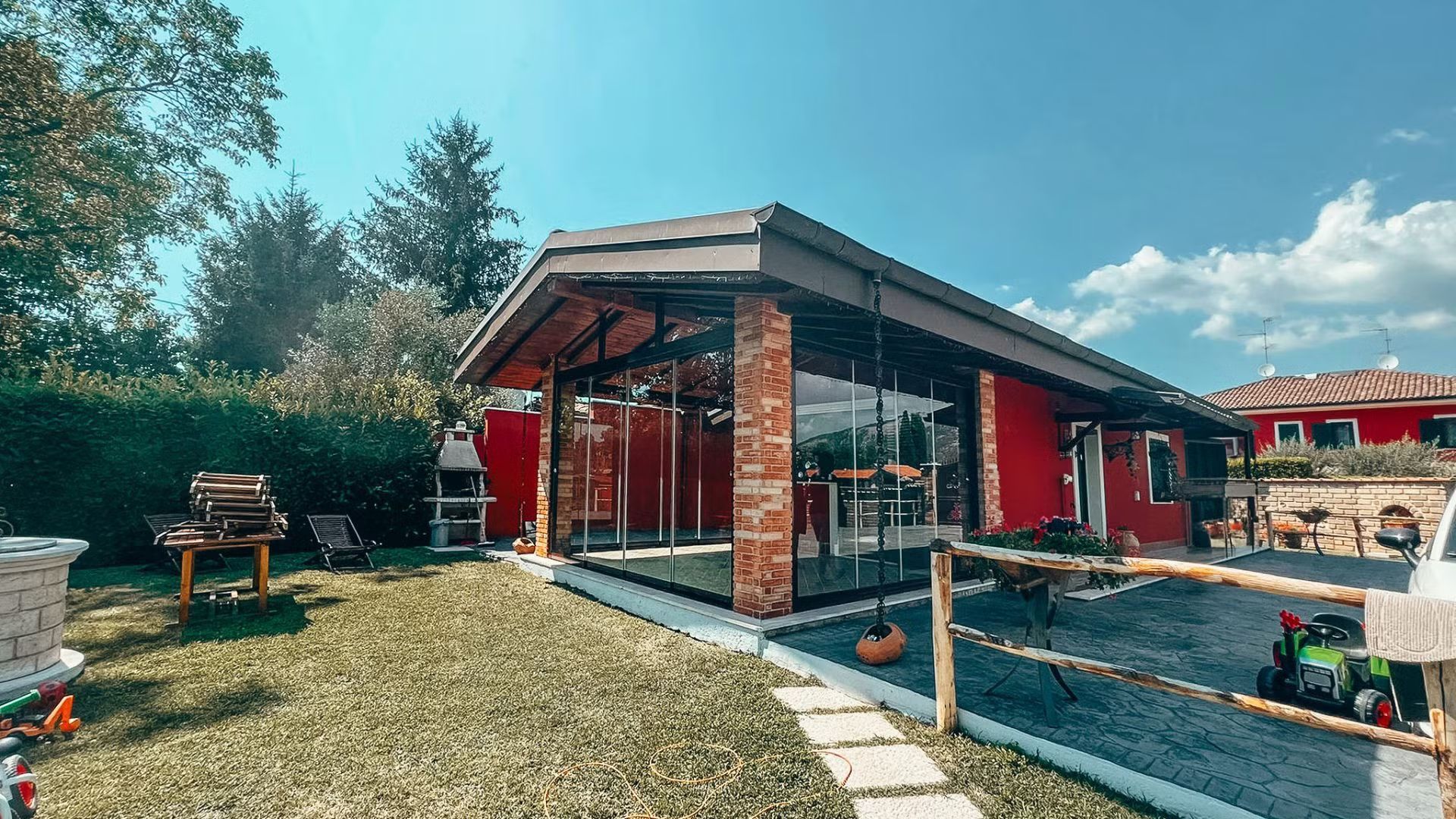 Una casa rossa con tante finestre si trova in mezzo a un rigoglioso campo verde.
