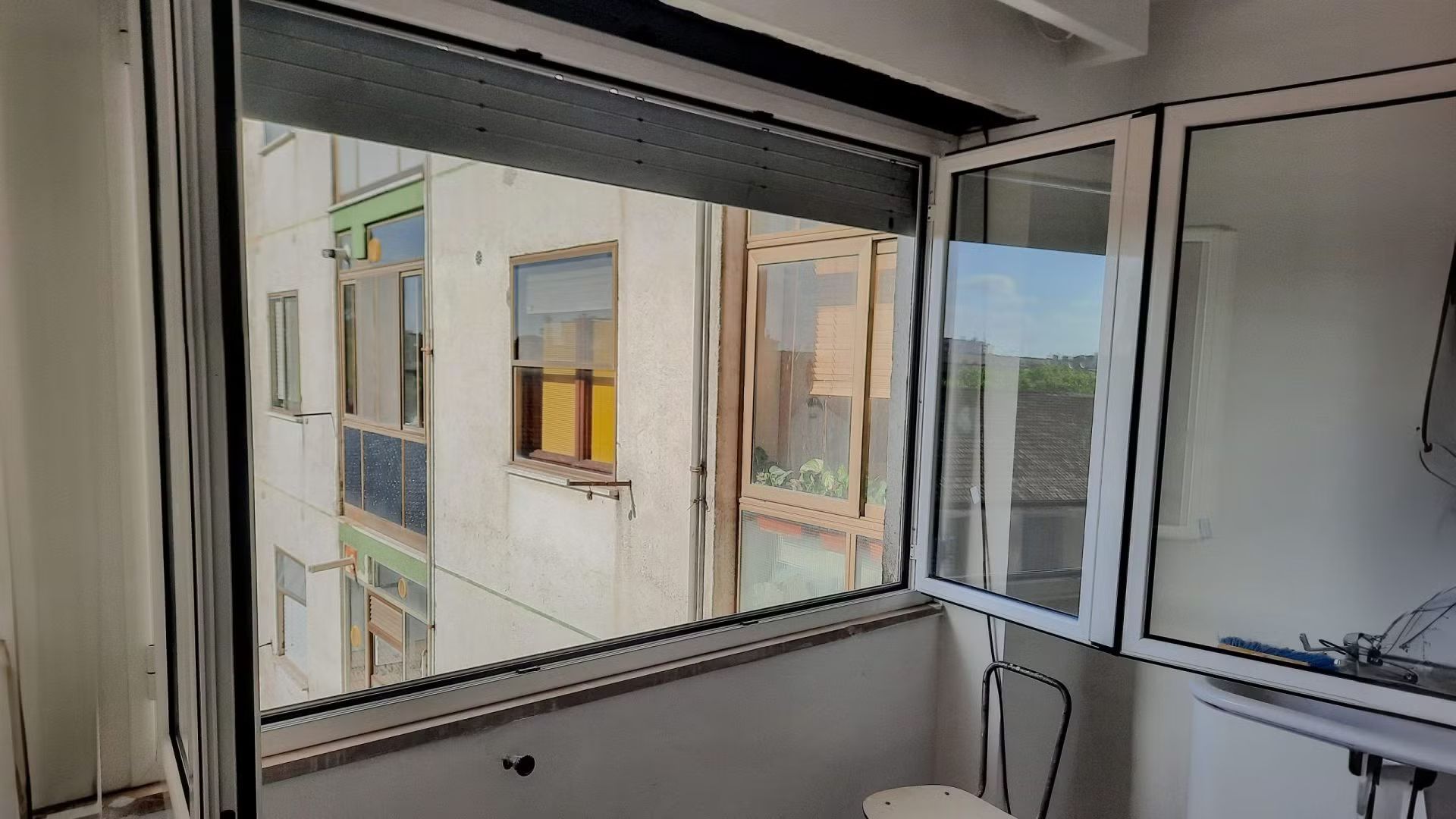 Una stanza con una grande finestra e una sedia di fronte.