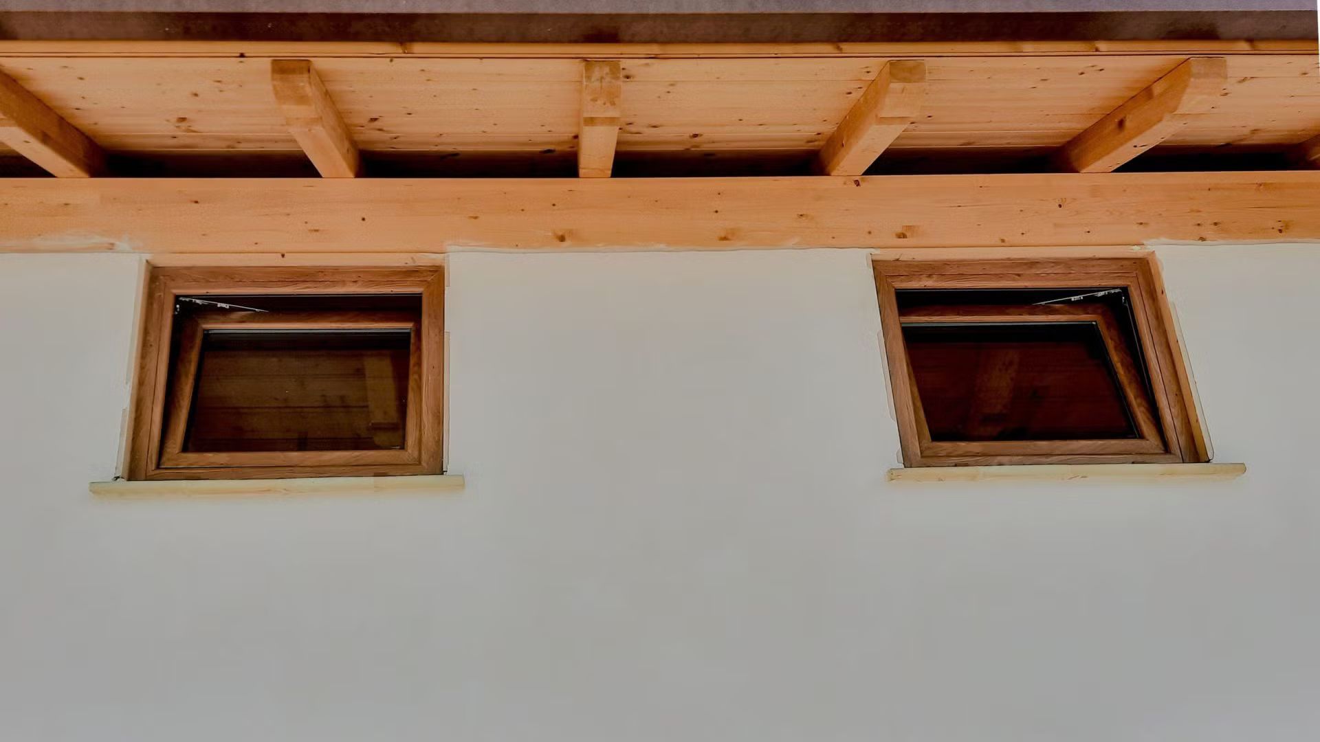 Ci sono due finestre sul lato di un edificio sotto un tetto di legno.