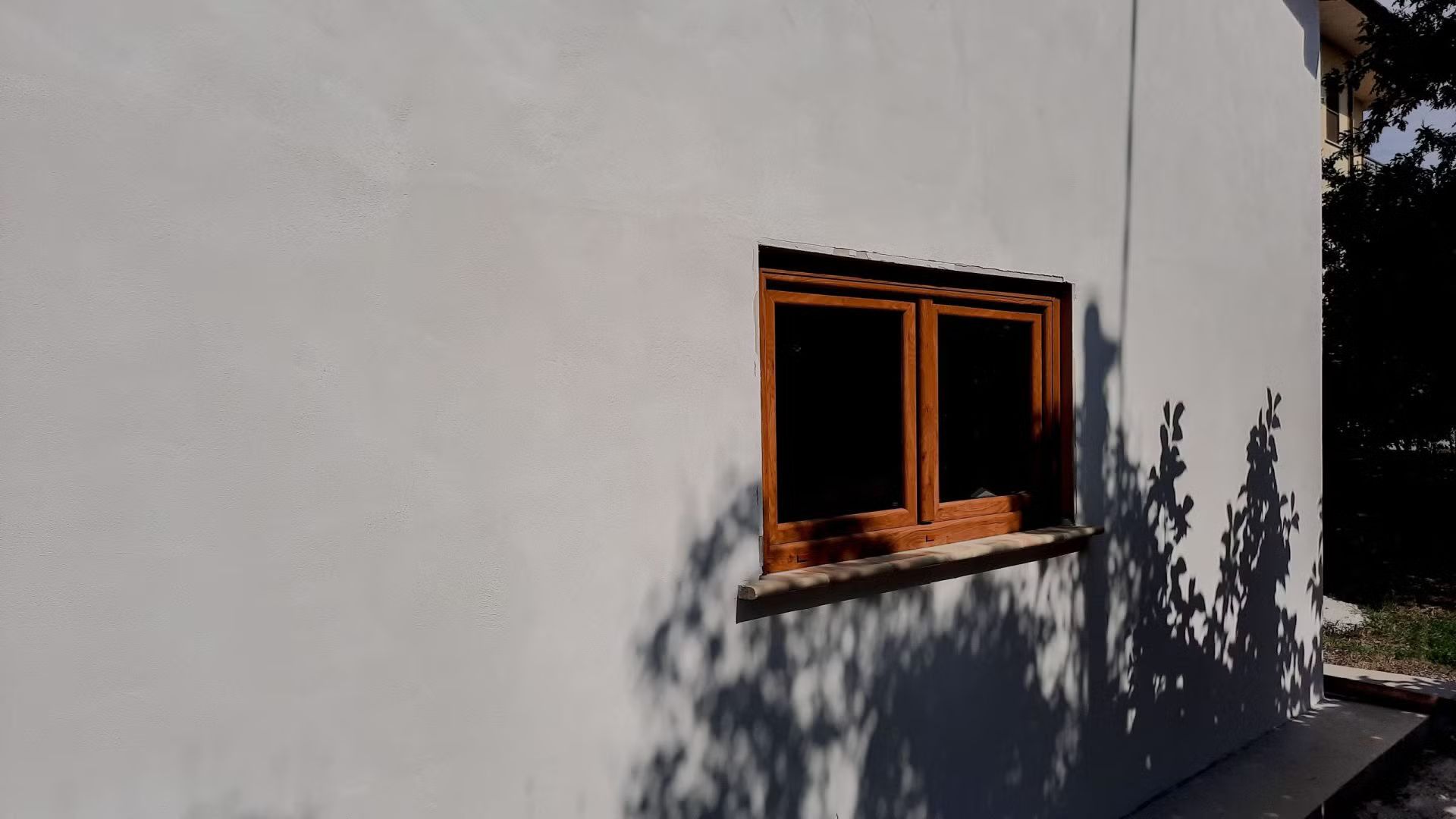 Un muro bianco con una finestra di legno.