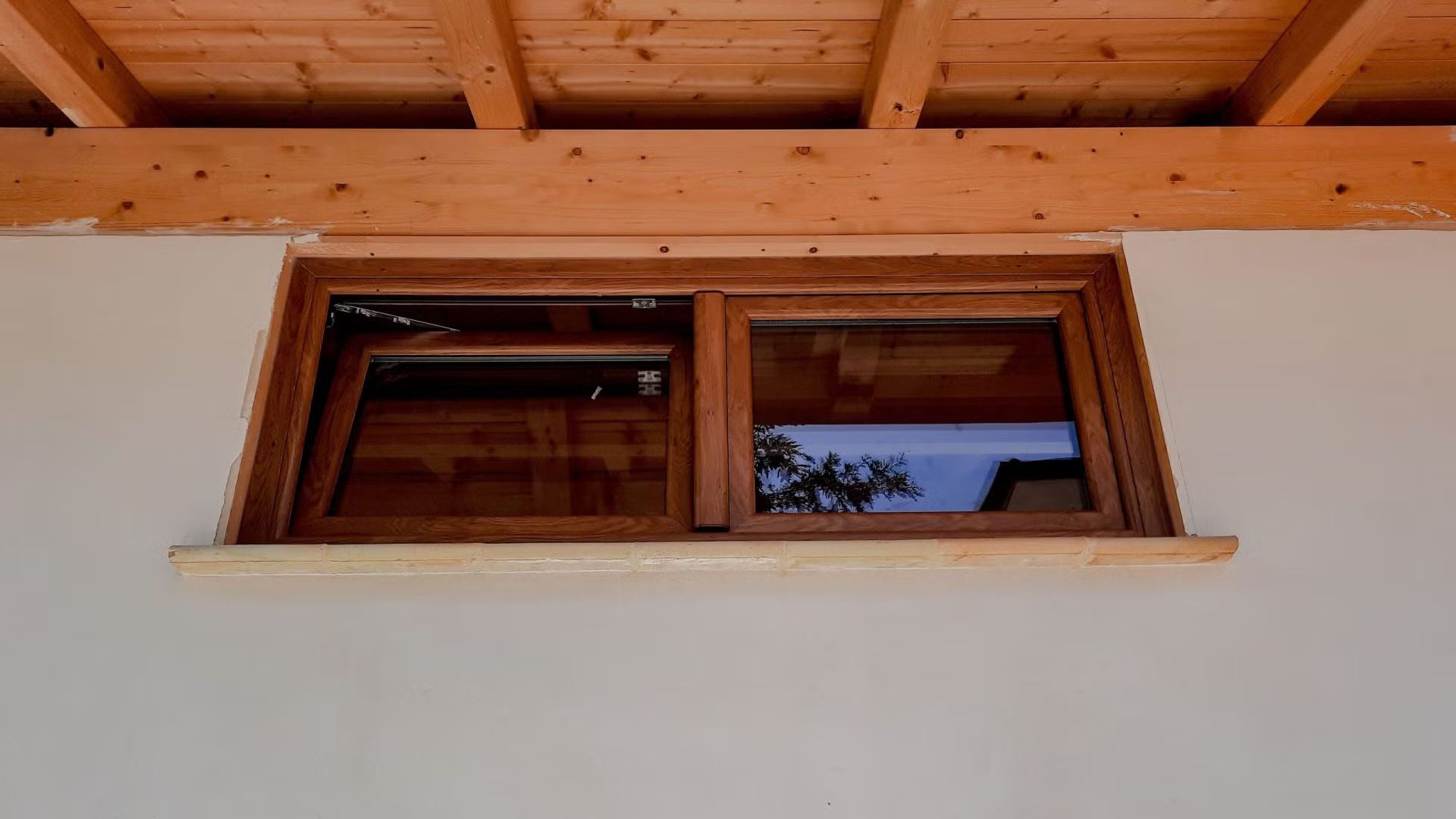 Una finestra di legno su un muro bianco sotto un tetto di legno.