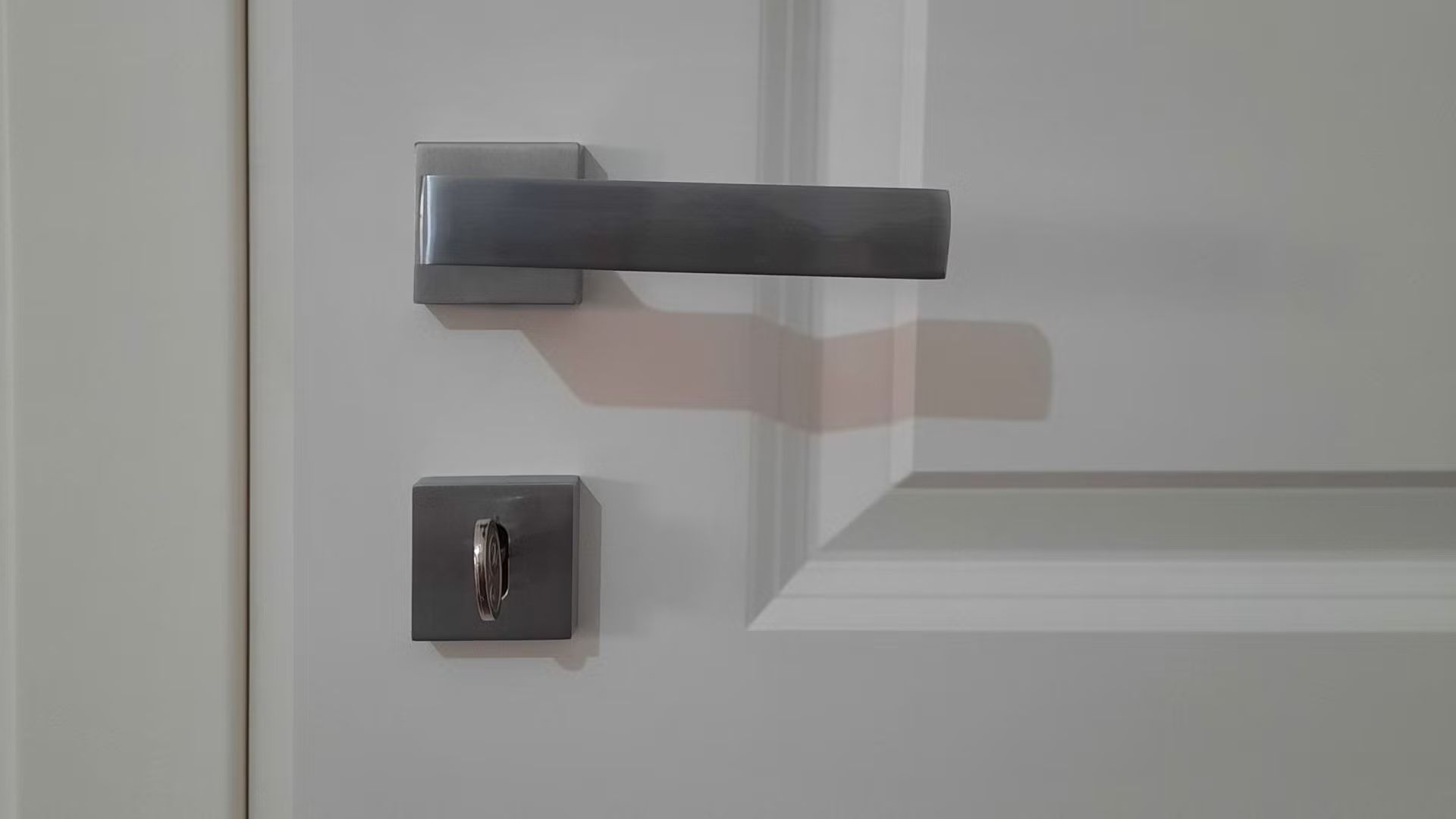 Un primo piano della maniglia di una porta bianca.