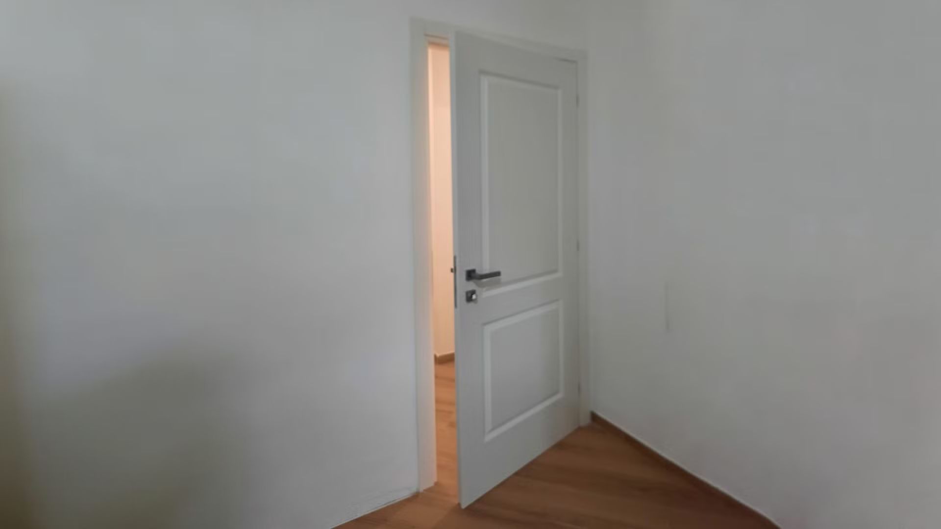 Una porta bianca è aperta in una stanza vuota.