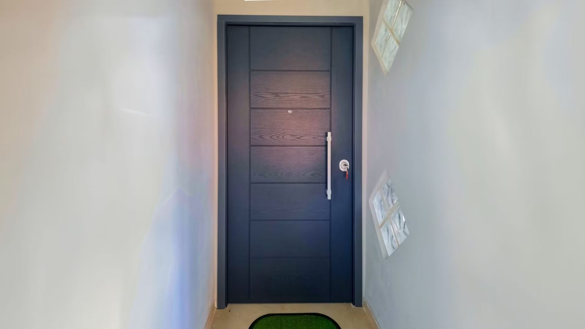 Una porta nera si trova in un corridoio accanto a un muro bianco.