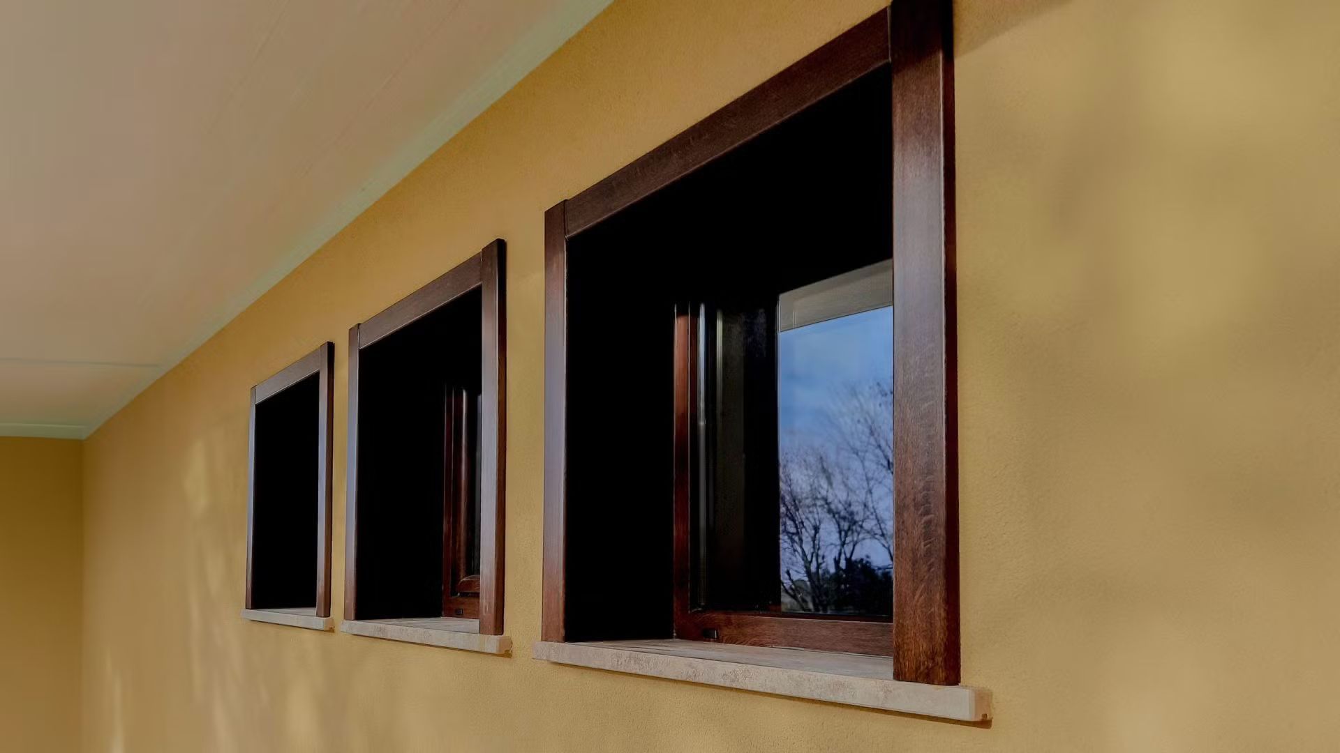 Tre finestre sono allineate su una parete gialla.