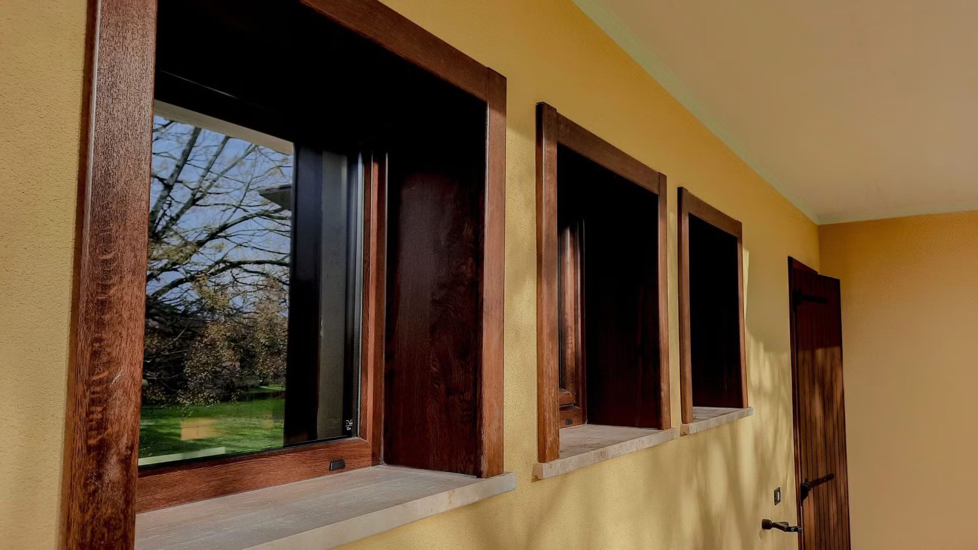 Una fila di finestre di legno su una parete gialla.