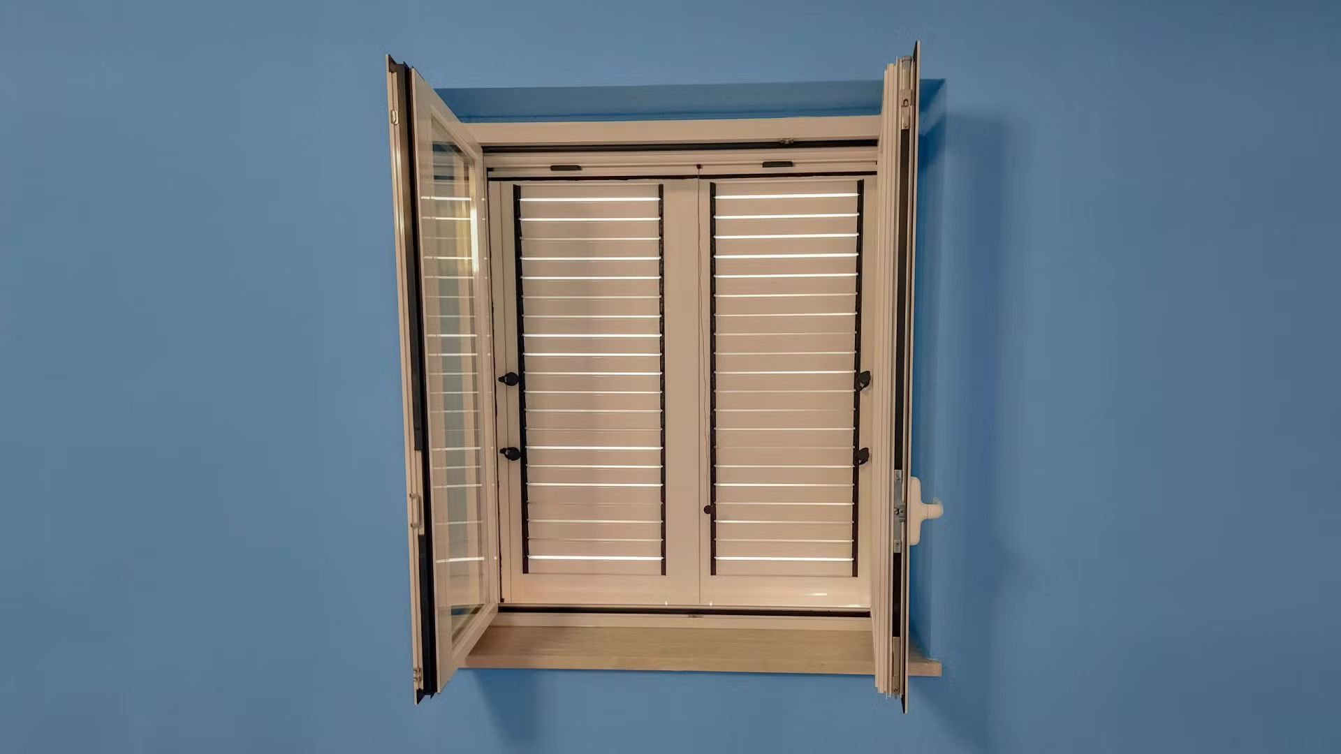 Una finestra bianca con le persiane è contro un muro blu