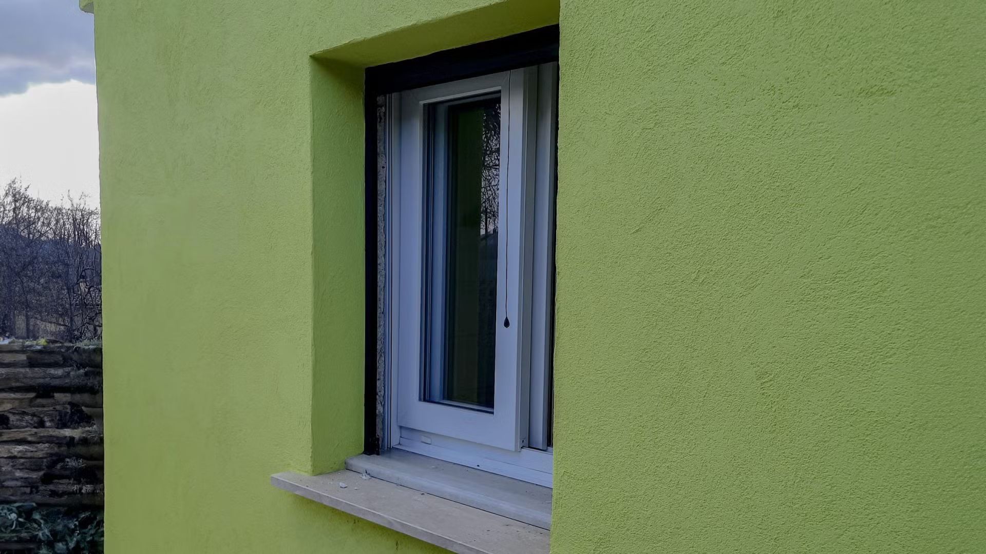 Un muro verde con una finestra bianca.