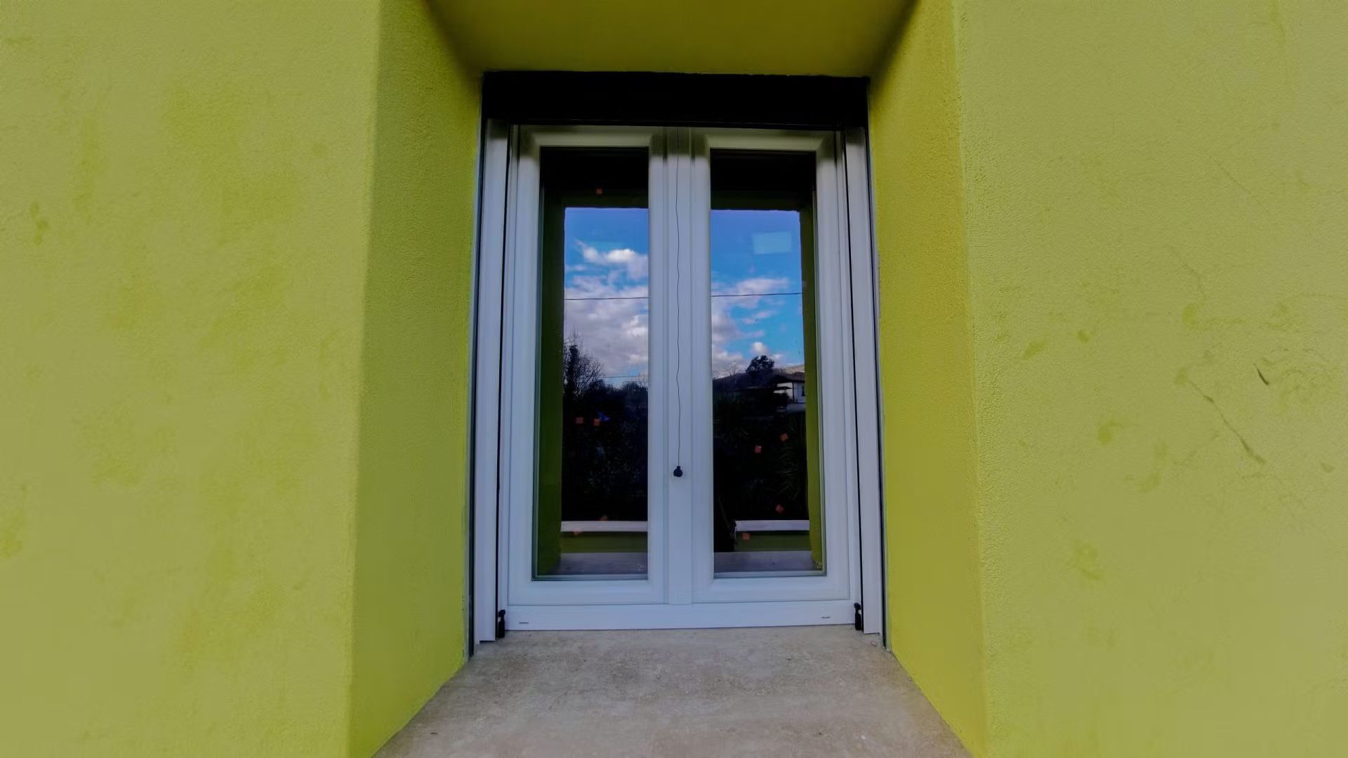 Un edificio giallo con una porta bianca e una finestra.