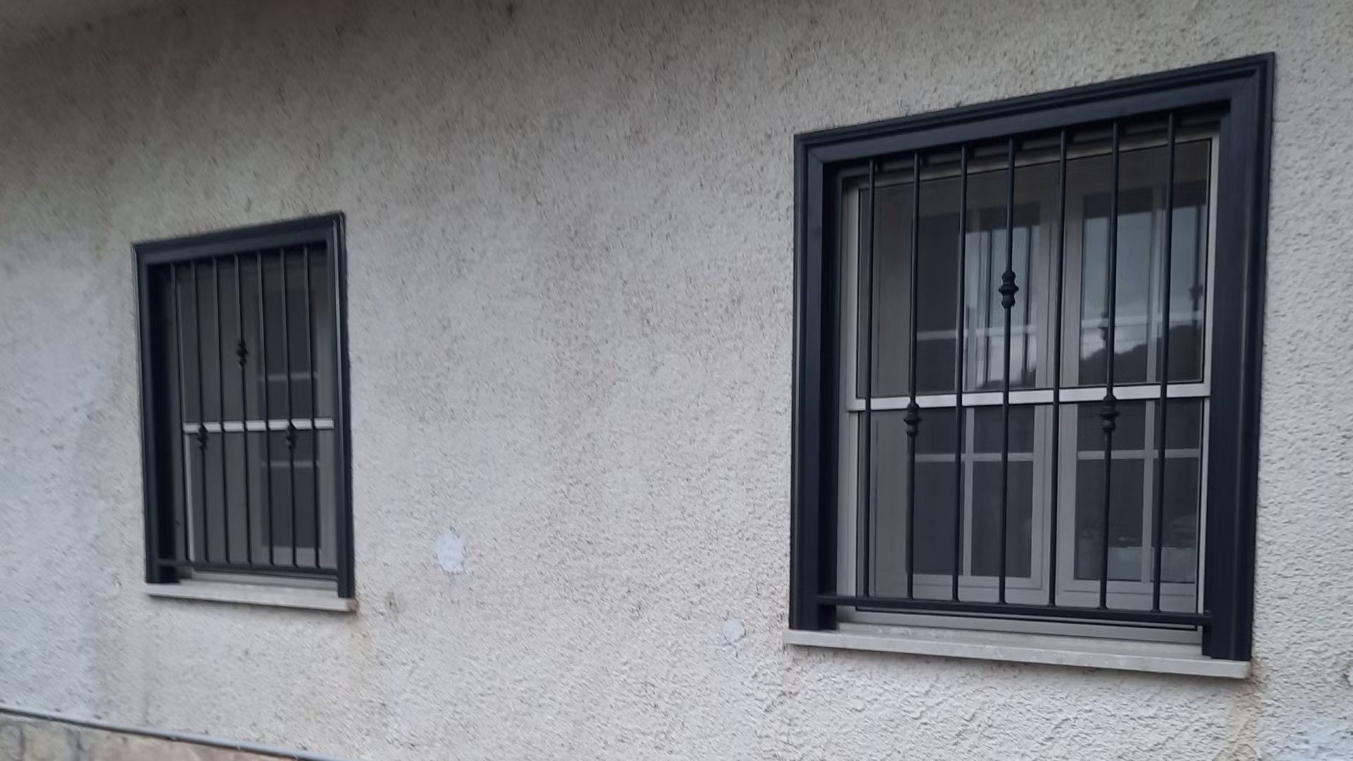 Due finestre con le sbarre sul lato di un edificio.