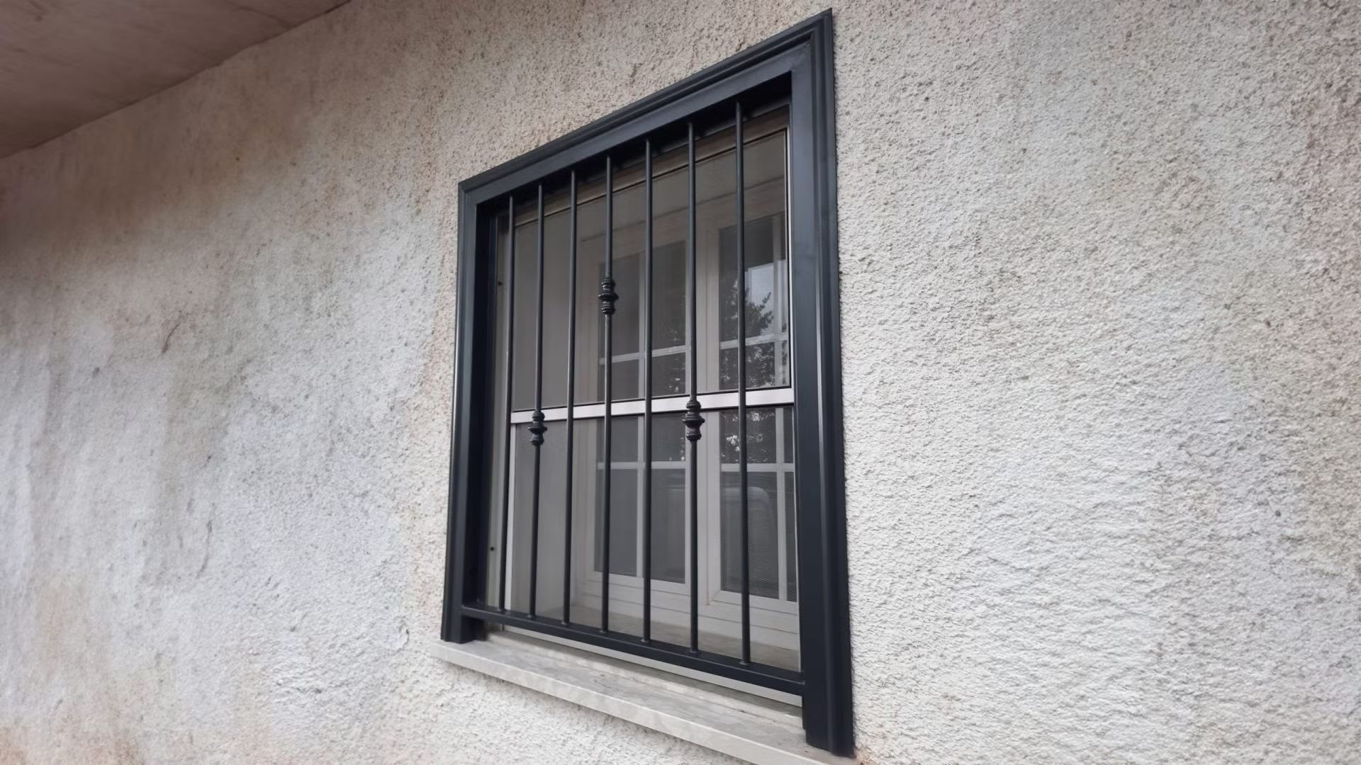 Una finestra con una griglia metallica sul lato di un edificio.