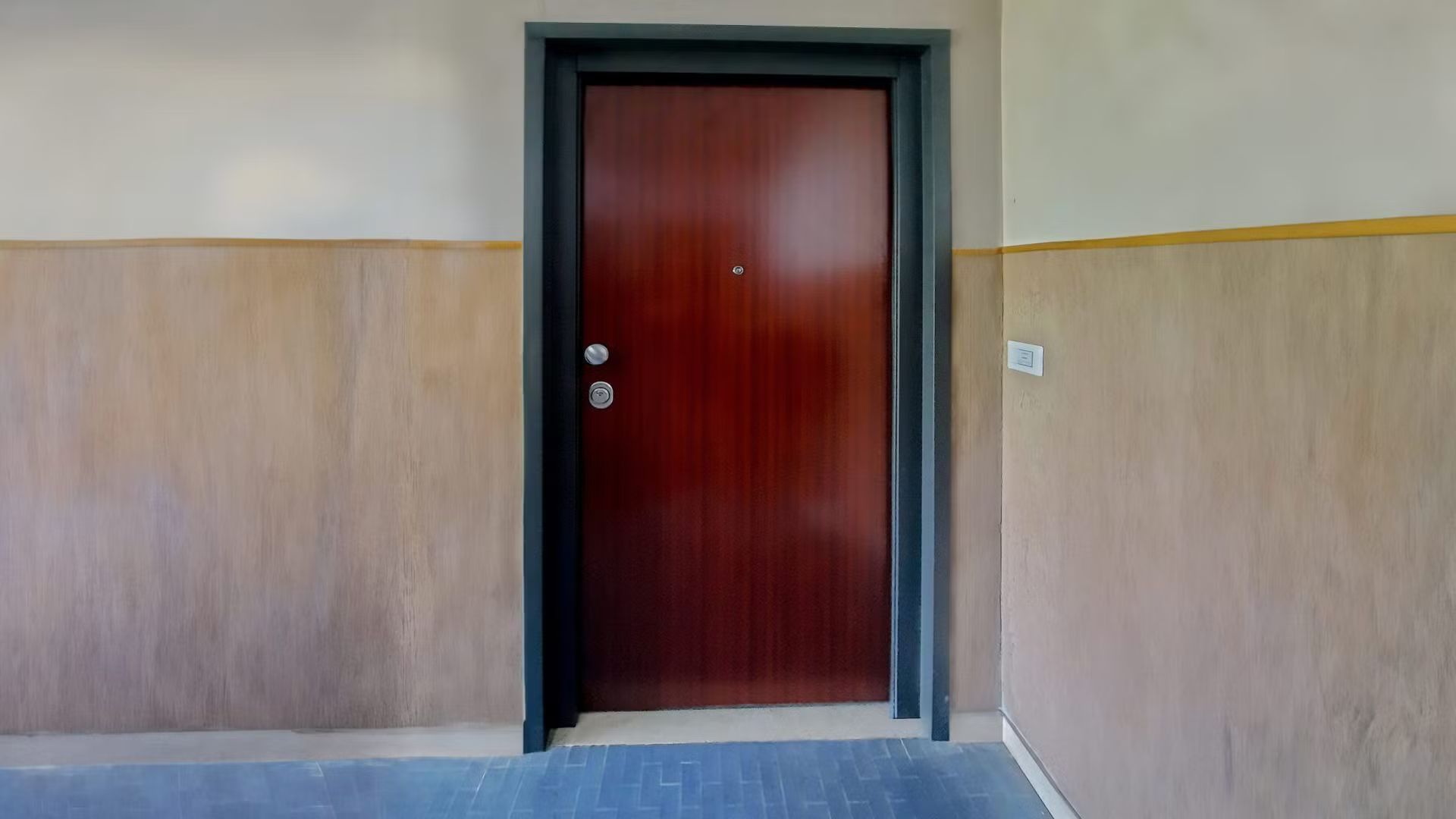 Una porta di legno è posizionata in un corridoio, accanto a un muro.