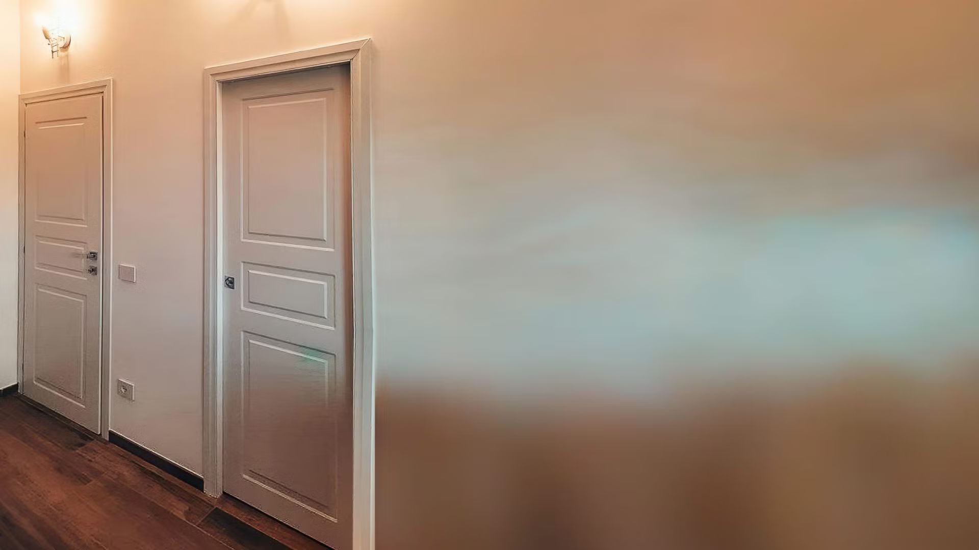 Un corridoio con due porte bianche e un pavimento in legno.
