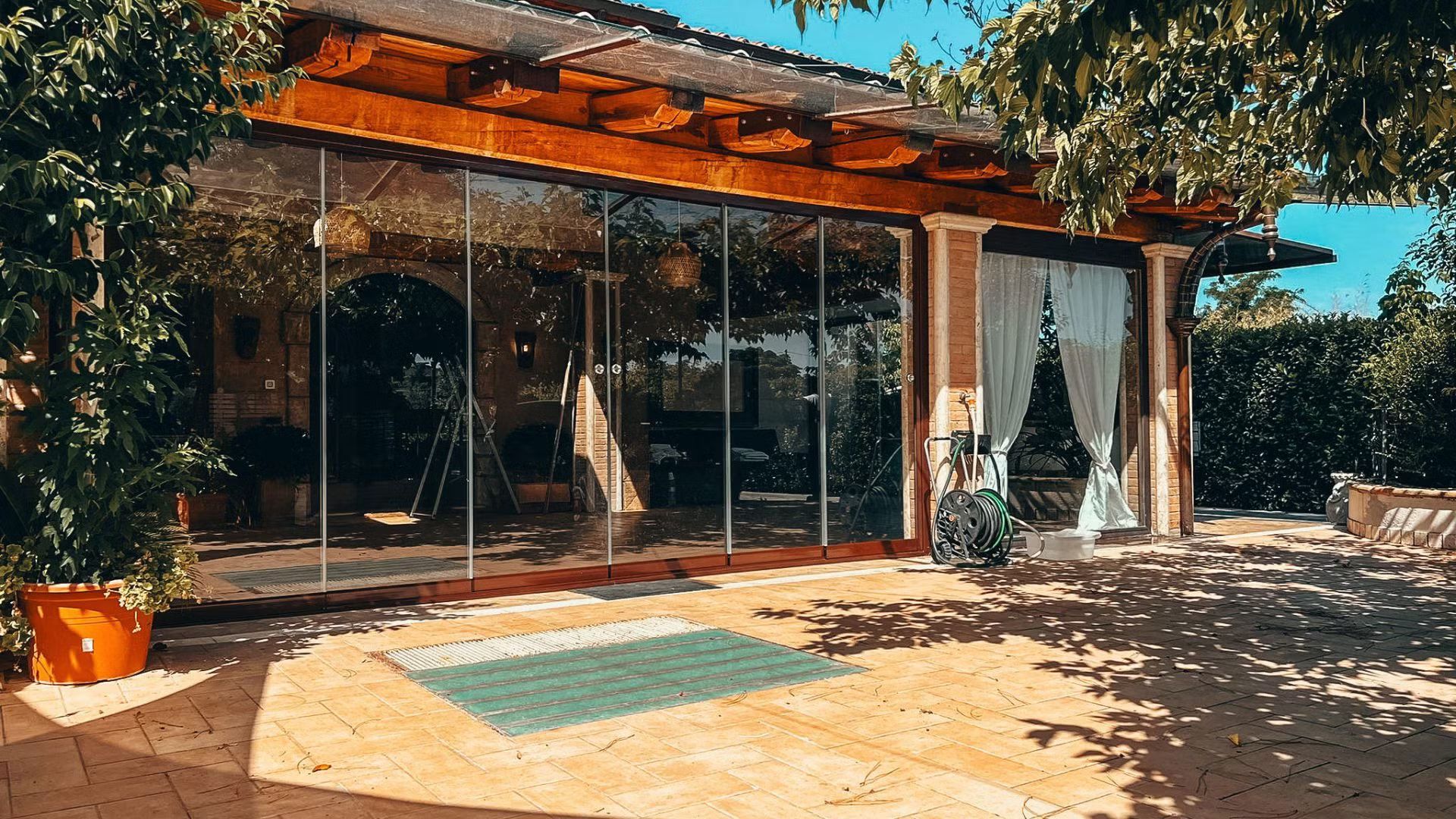 Una grande casa con molte finestre e un patio davanti.