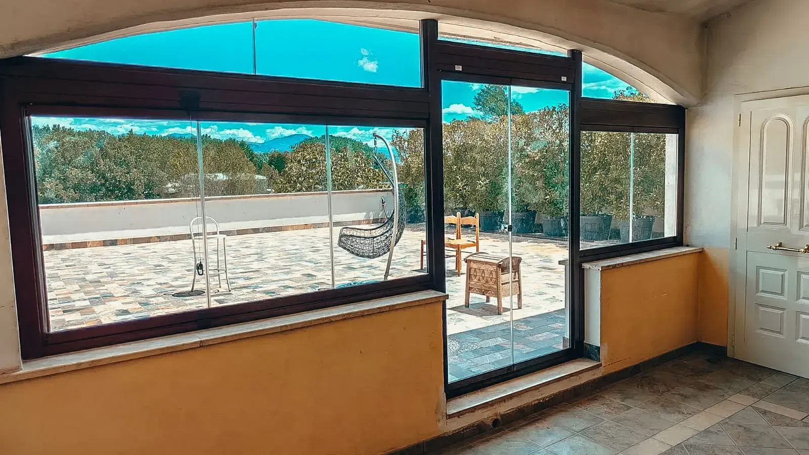 Una stanza con molte finestre e un patio sullo sfondo.