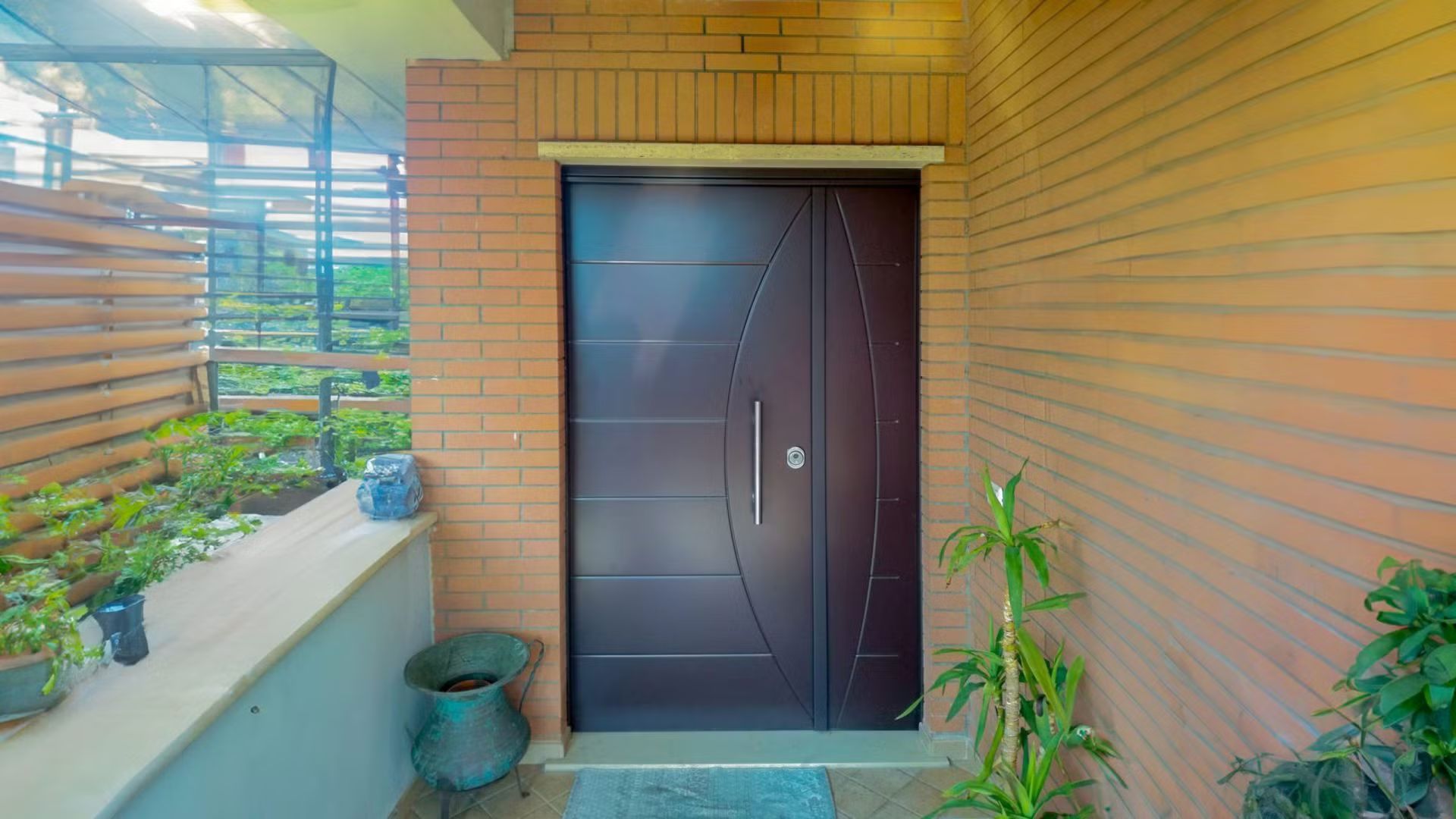 Un muro di mattoni con una porta marrone e una pianta in vaso di fronte.