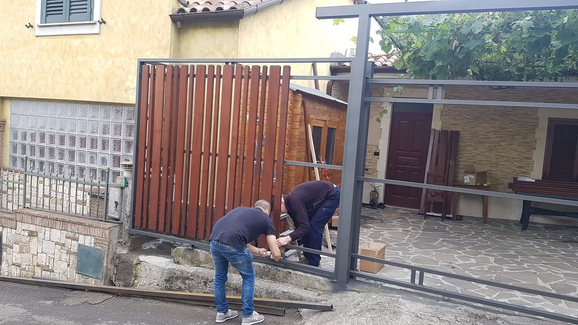 Due uomini stanno lavorando su una recinzione davanti a una casa