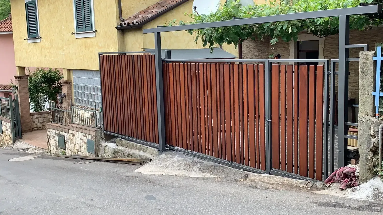 Una staccionata di legno è davanti a una casa gialla