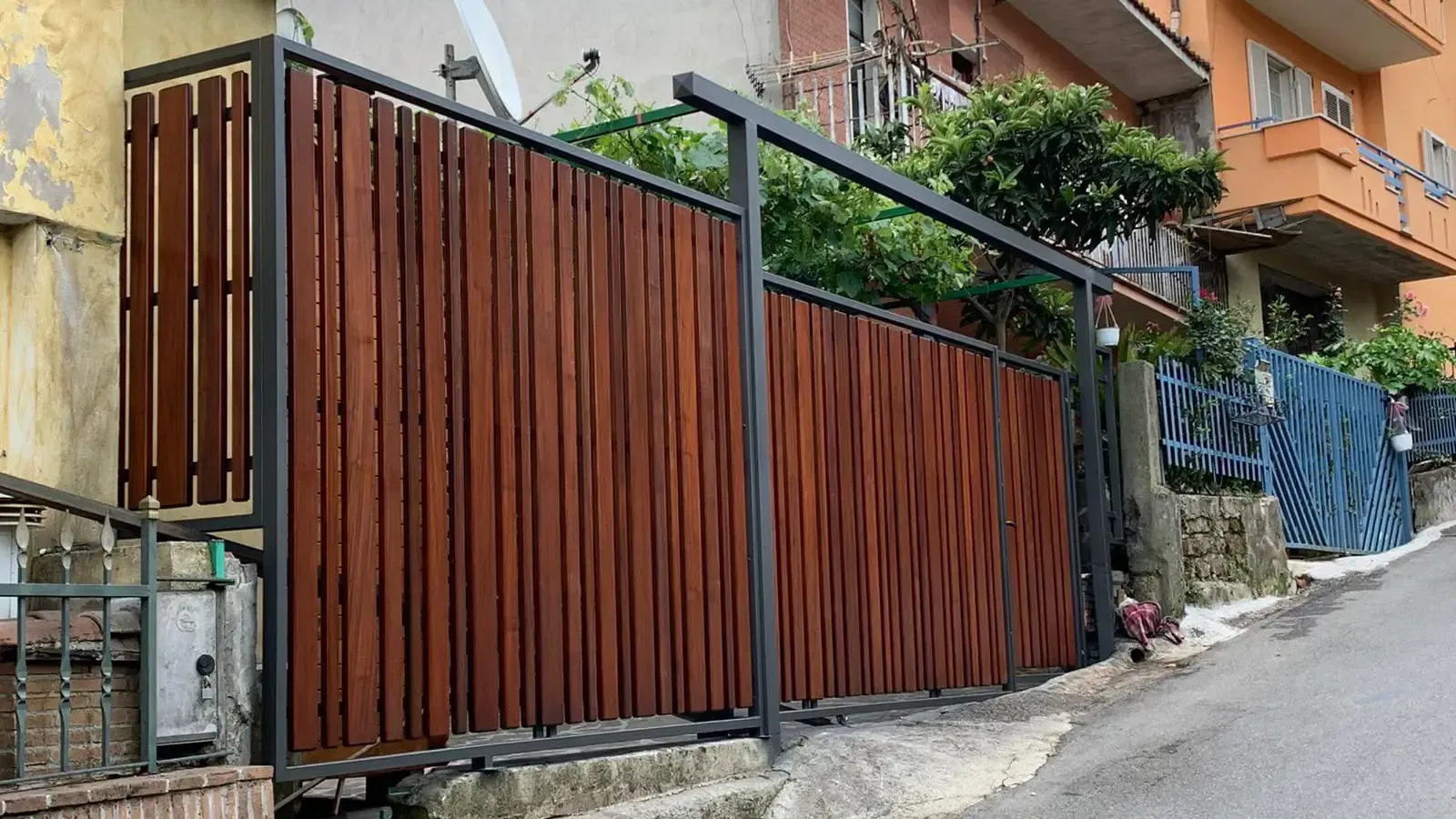 Una staccionata di legno è posta sul fianco di una collina accanto a un edificio.