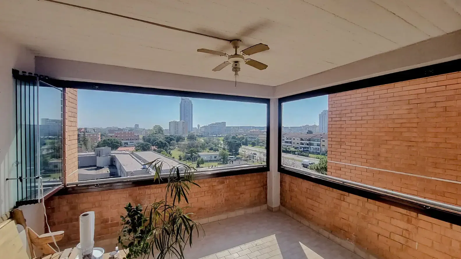 Un balcone con vista sulla città e un ventilatore a soffitto.