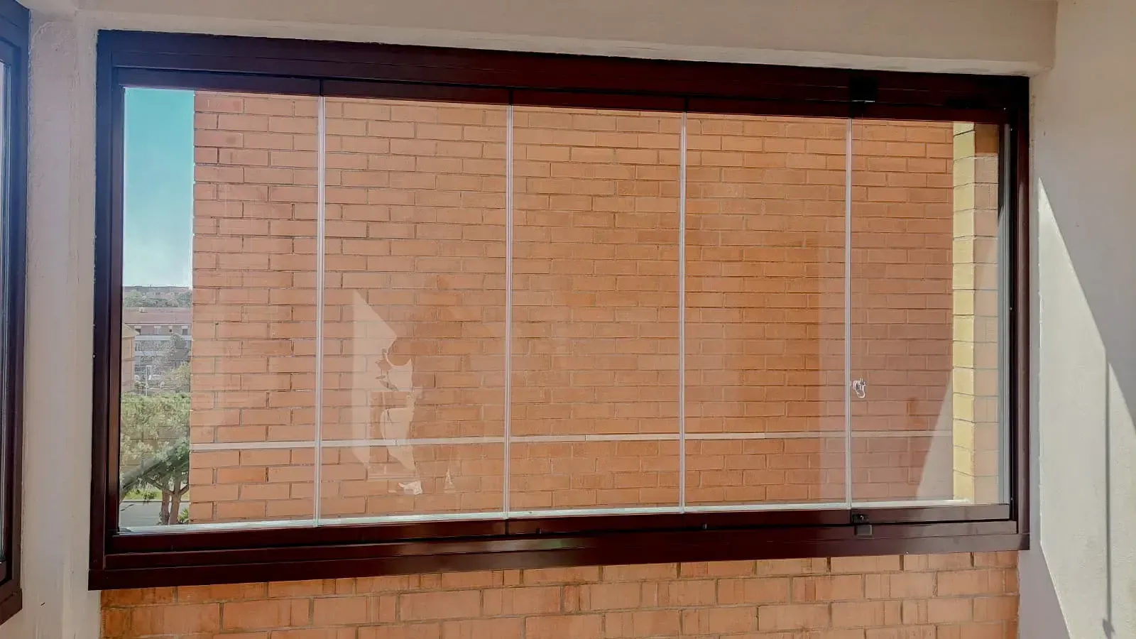 Una grande finestra in una stanza con un muro di mattoni dietro.