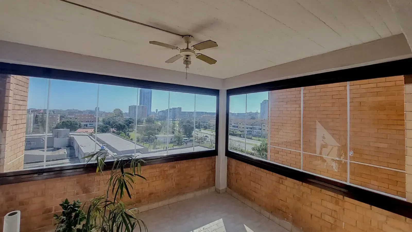 Una stanza con molte finestre e un ventilatore a soffitto.