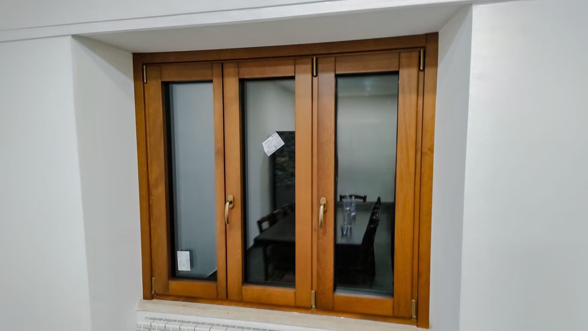 Una finestra di legno in una stanza con una parete bianca