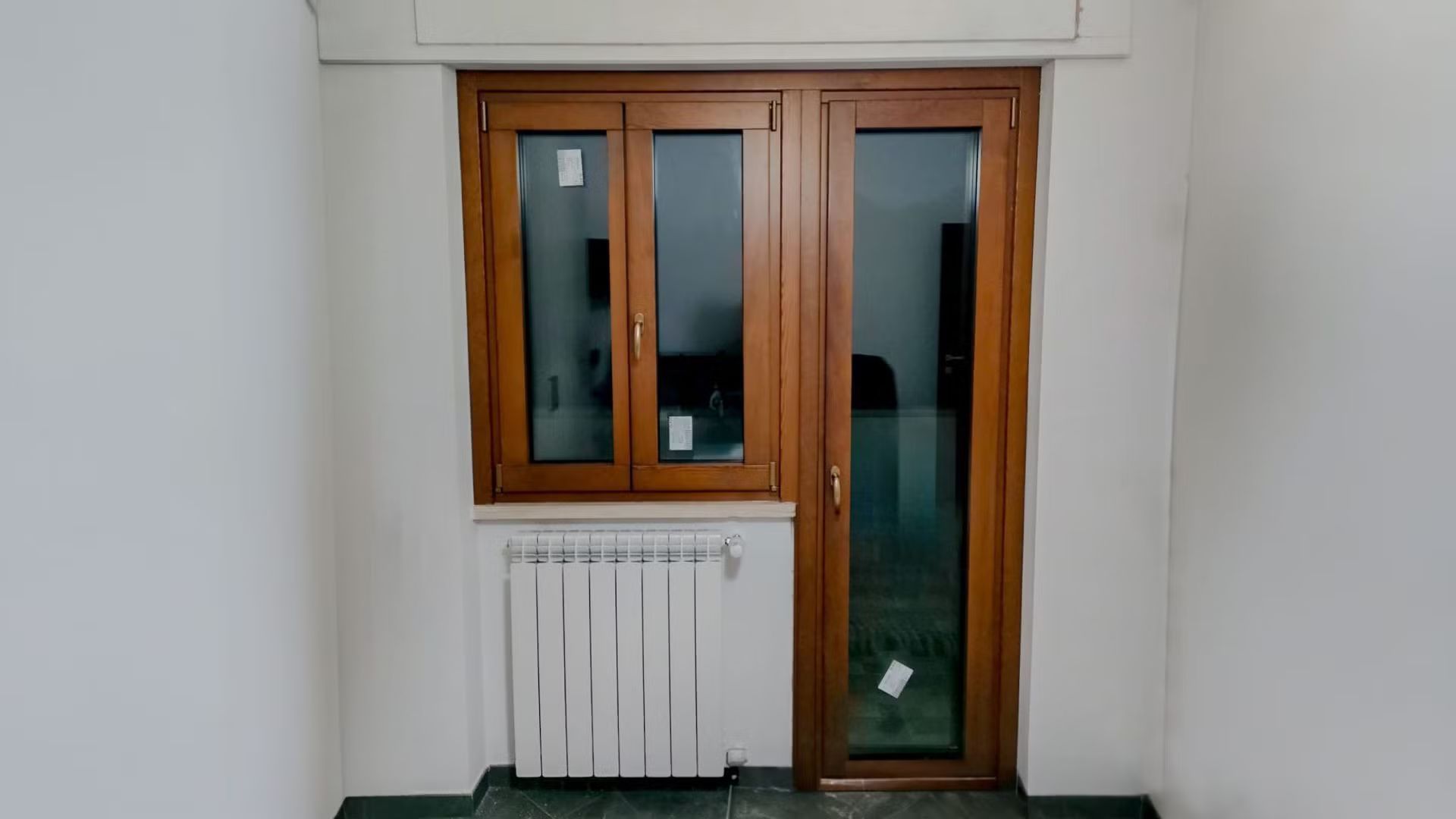 Una stanza vuota con una porta di legno e un termosifone.