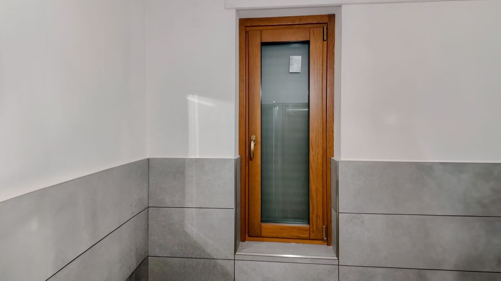 Un bagno con una porta di legno e una finestra di vetro.
