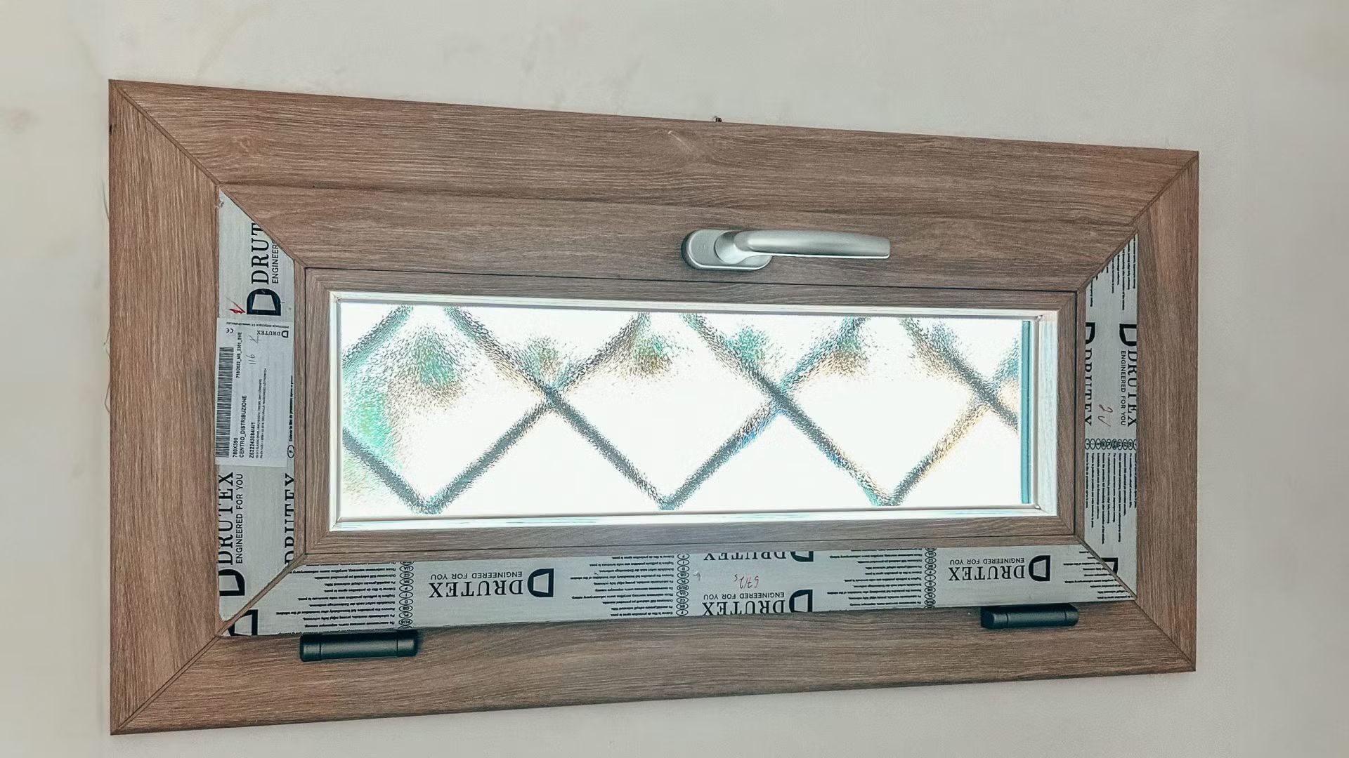 Una finestra con una cornice di legno è appesa a una parete.