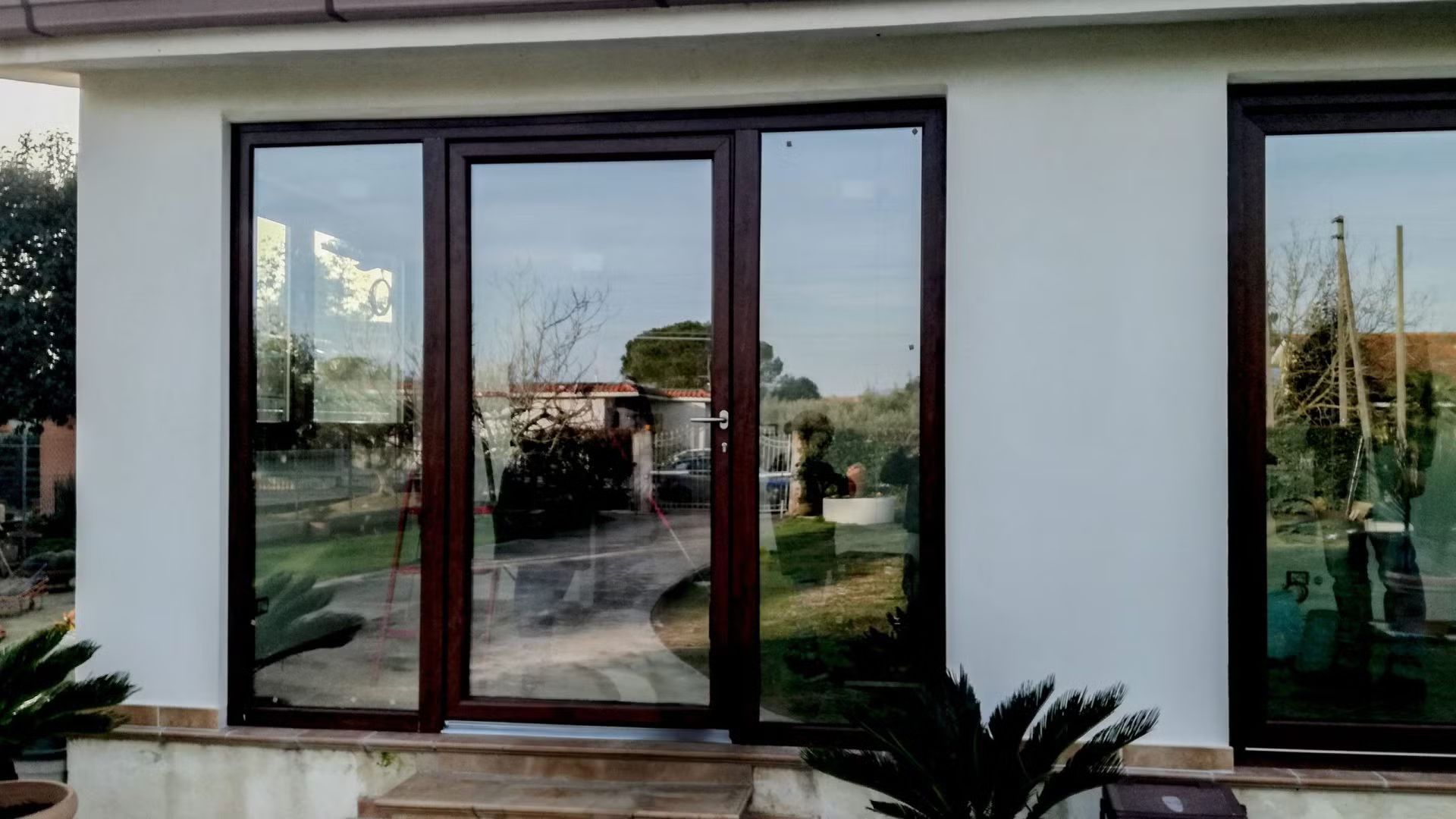 Una casa con molte finestre e il riflesso degli alberi sulle finestre.