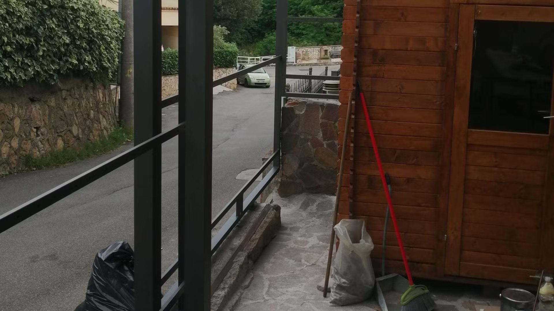 Una baracca di legno con una scopa e un sacco di terra davanti.