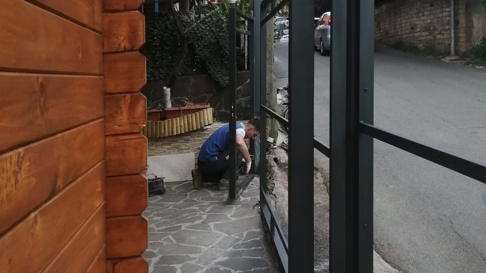 Un uomo sta lavorando su una recinzione accanto a un edificio in legno.