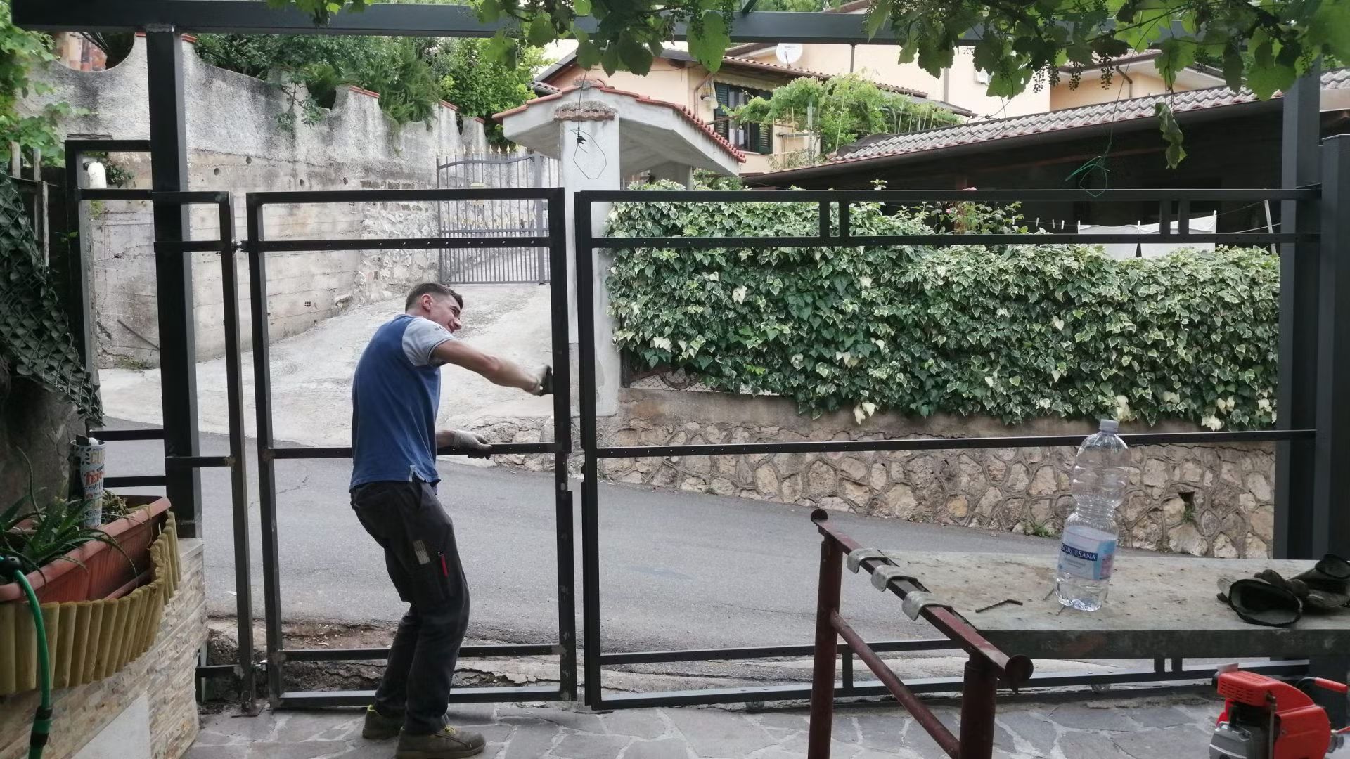 Un uomo con una camicia blu sta lavorando a un cancello